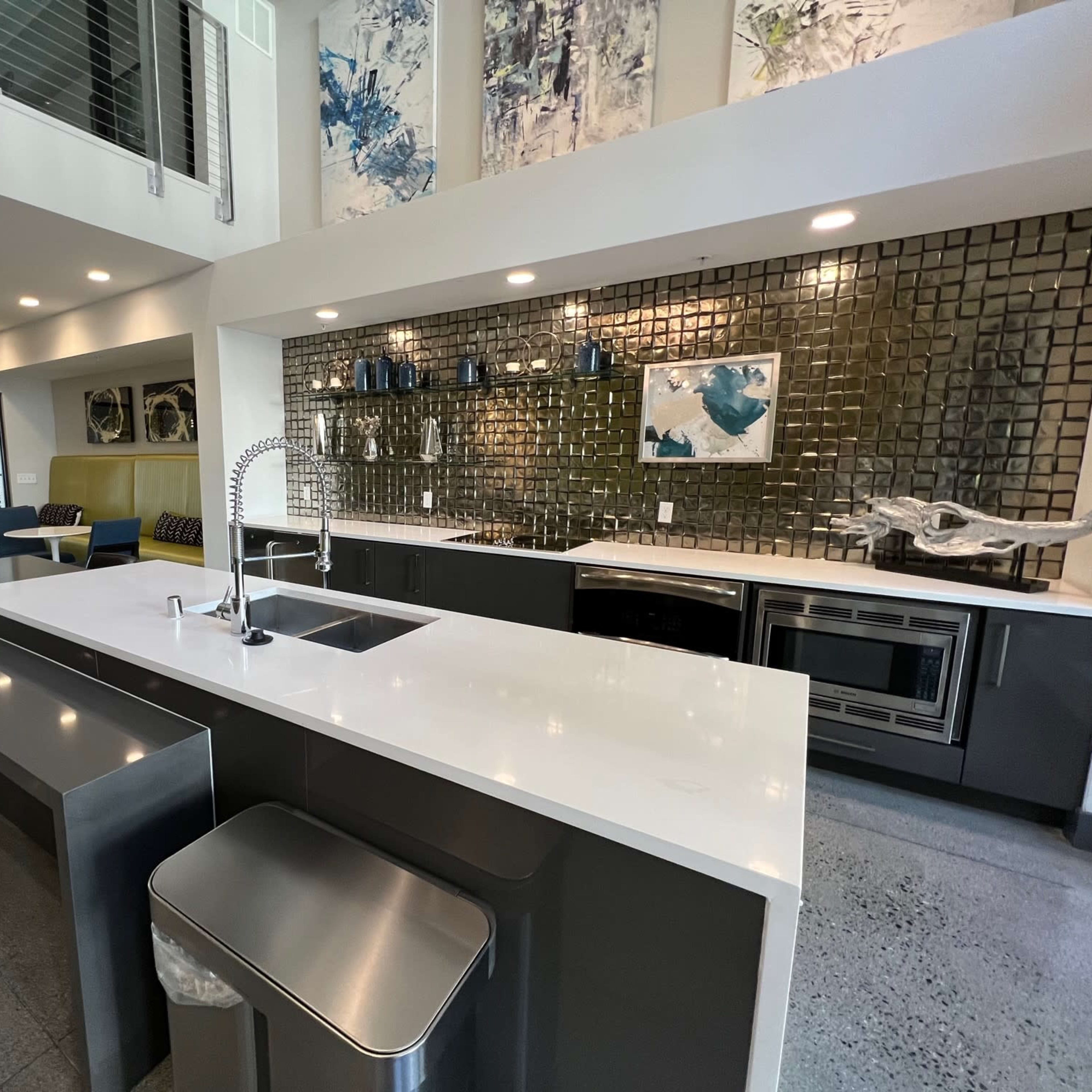 A modern kitchen with a large island, sleek cabinetry, stainless steel appliances, and a mosaic tile backsplash.