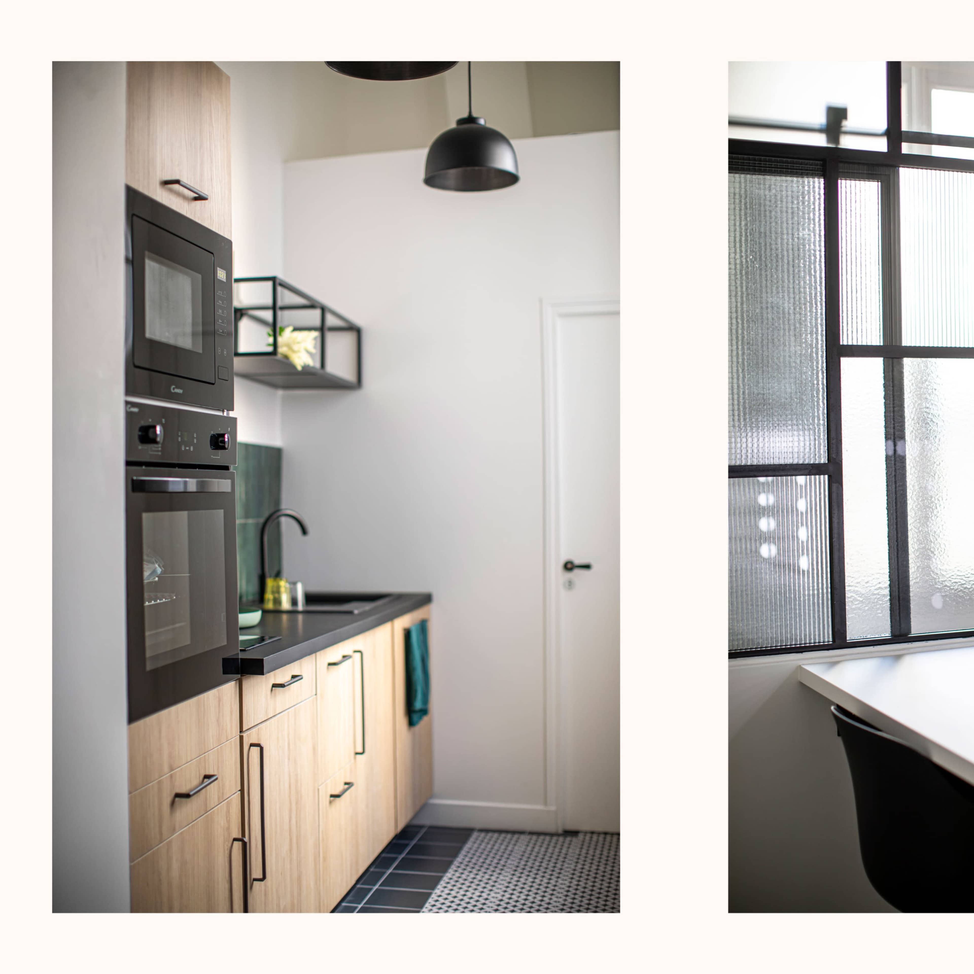 A modern kitchen on the left with wooden cabinets and built-in appliances, and a bright workspace on the right featuring a mirror with lights beside a window.