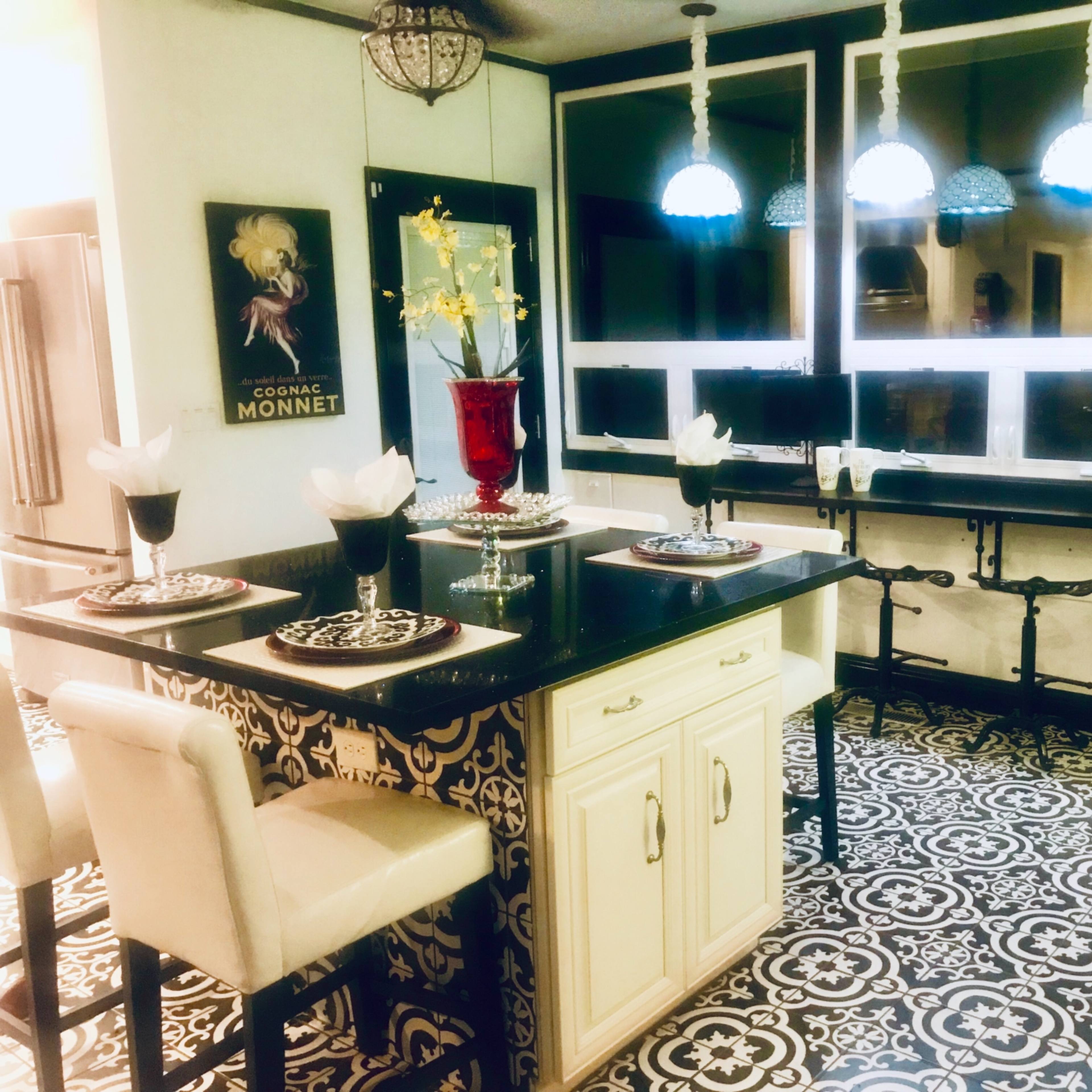A kitchen with a patterned floor, an island with seating, and three blue pendant lights hanging above.