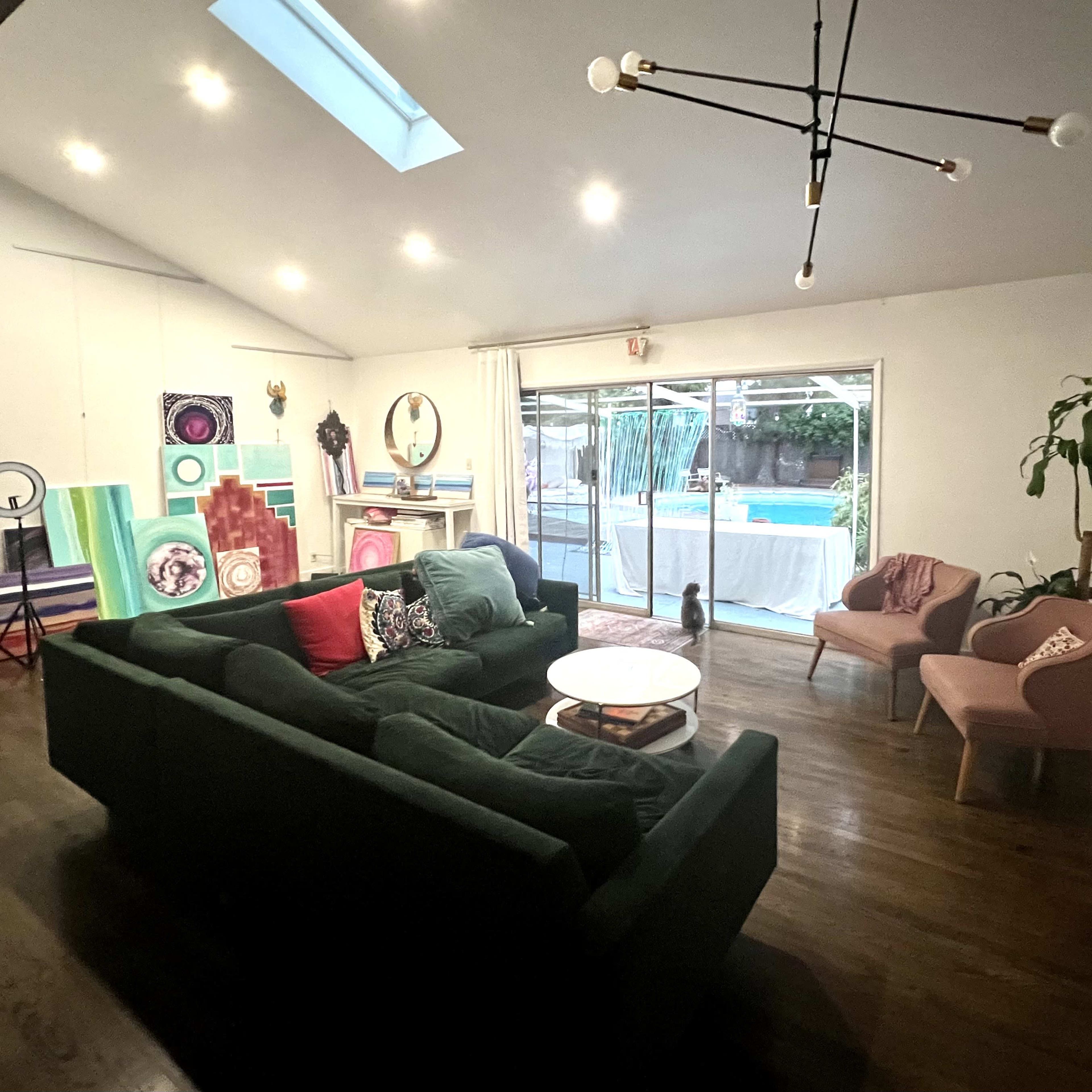 A modern living room features a sectional sofa, chairs, and a large glass door leading to a pool area.