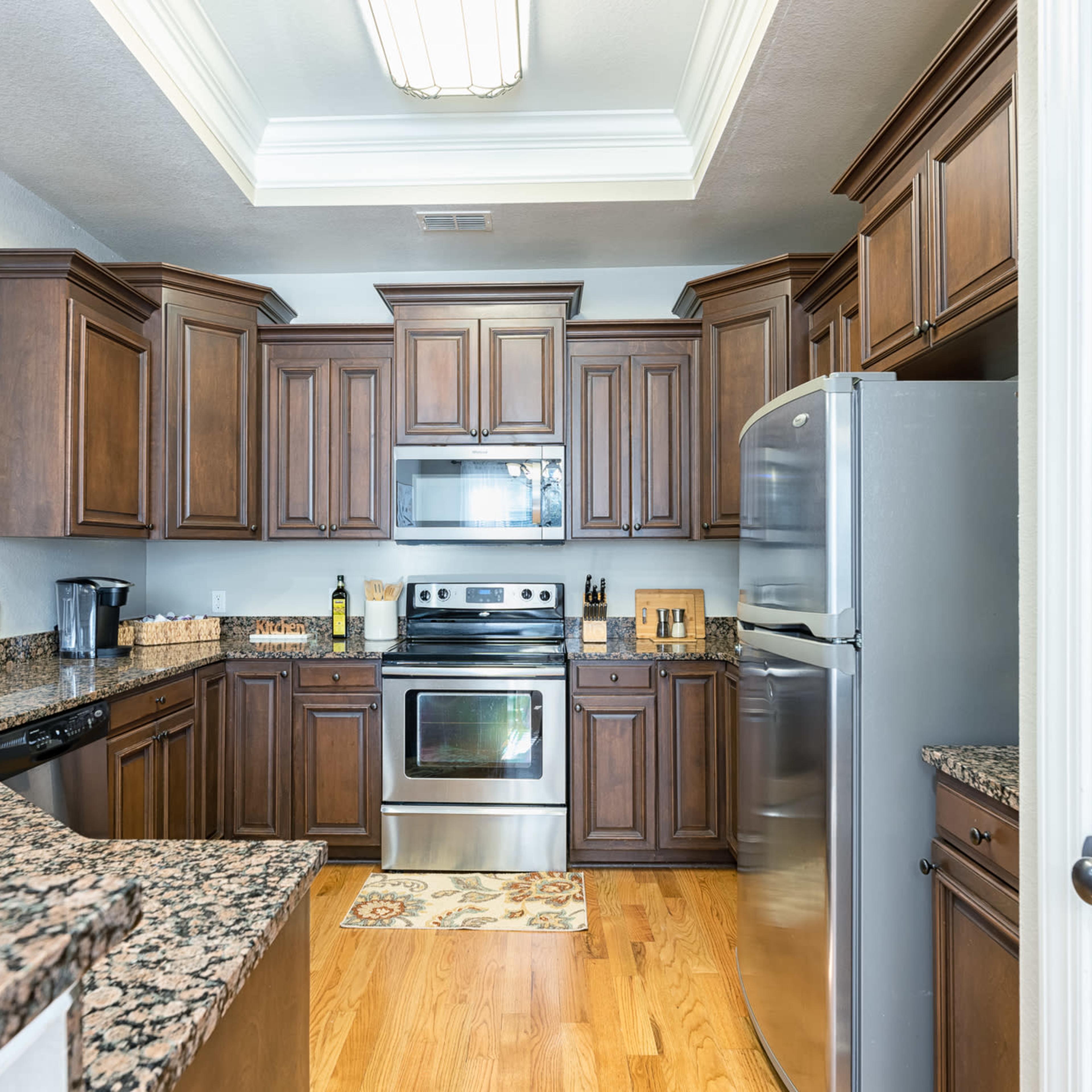 A modern kitchen featuring dark wood cabinets, stainless steel appliances, and granite countertops.
