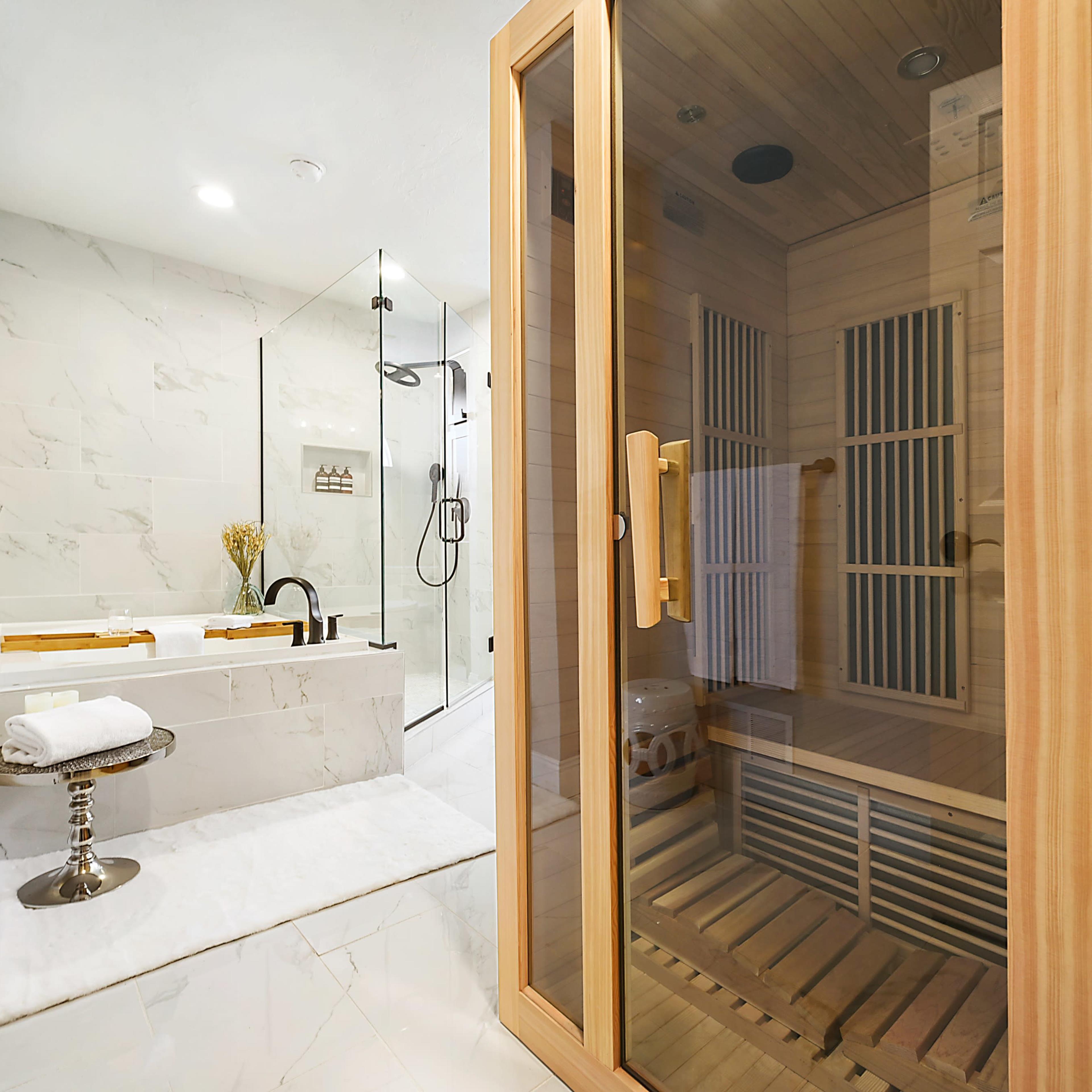 A modern bathroom featuring a wooden sauna, a freestanding bathtub, and a glass shower enclosure.