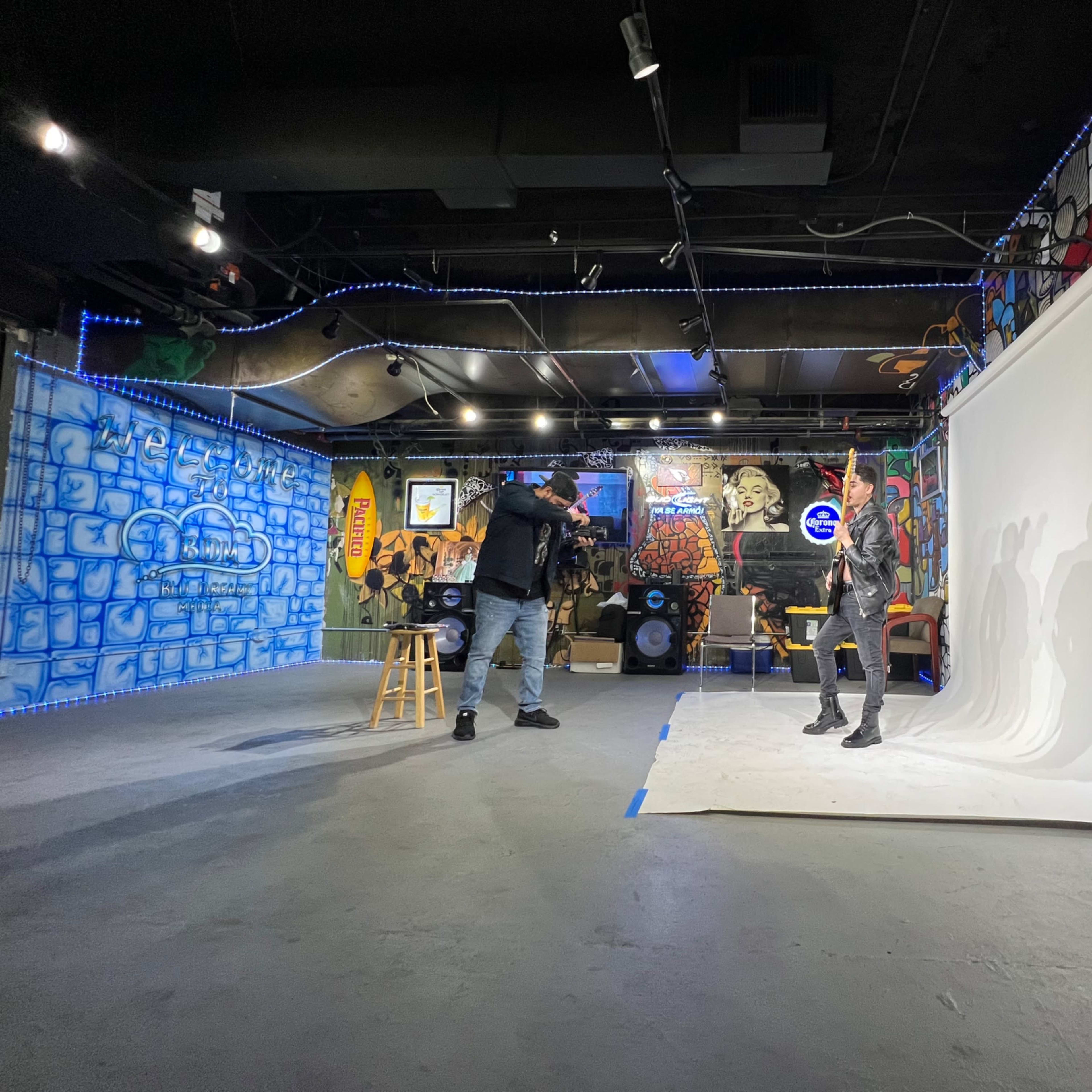 A photographer captures a model posing against a white backdrop in a creatively decorated studio featuring colorful murals.