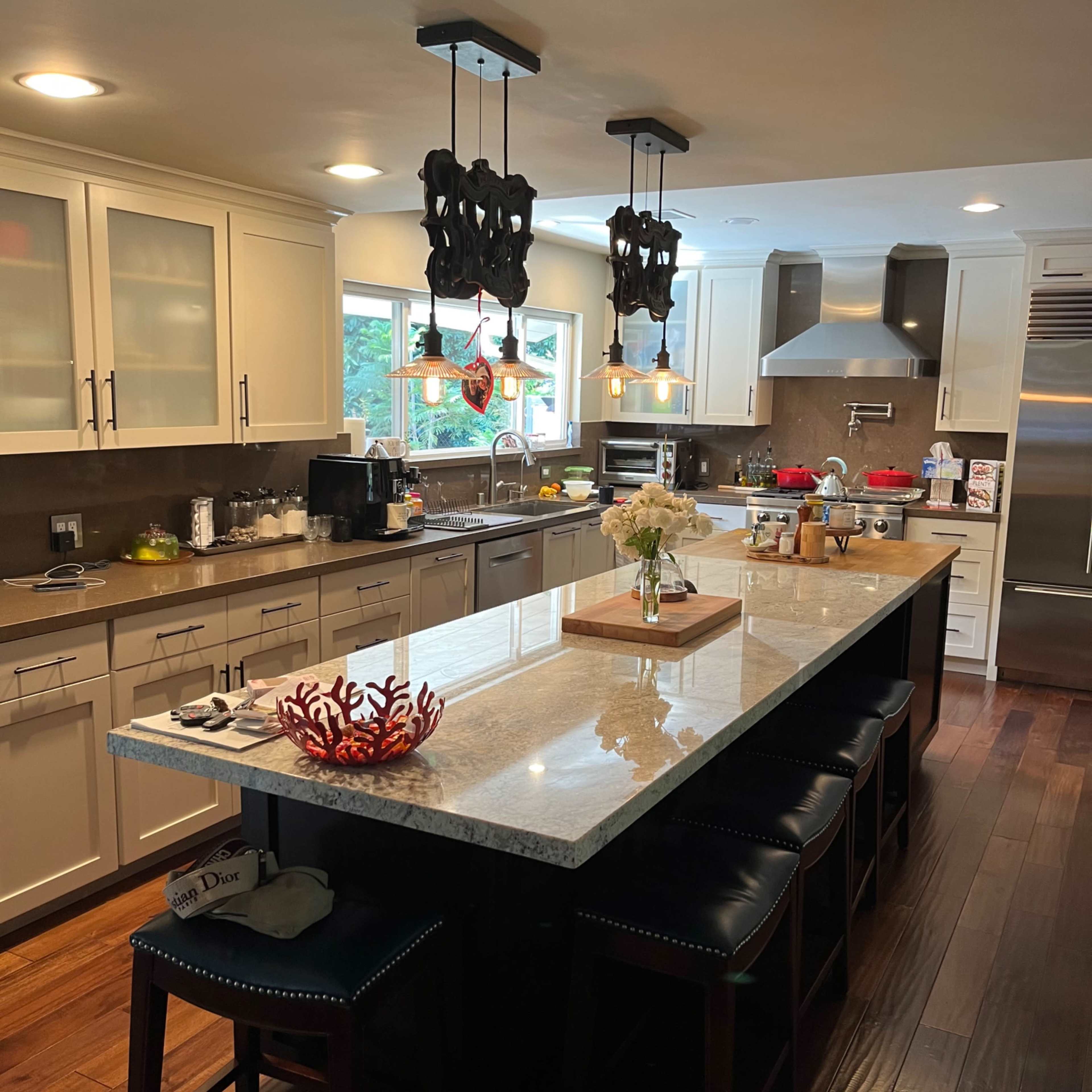 A modern kitchen featuring a large island with bar stools, granite countertops, and pendant lighting.