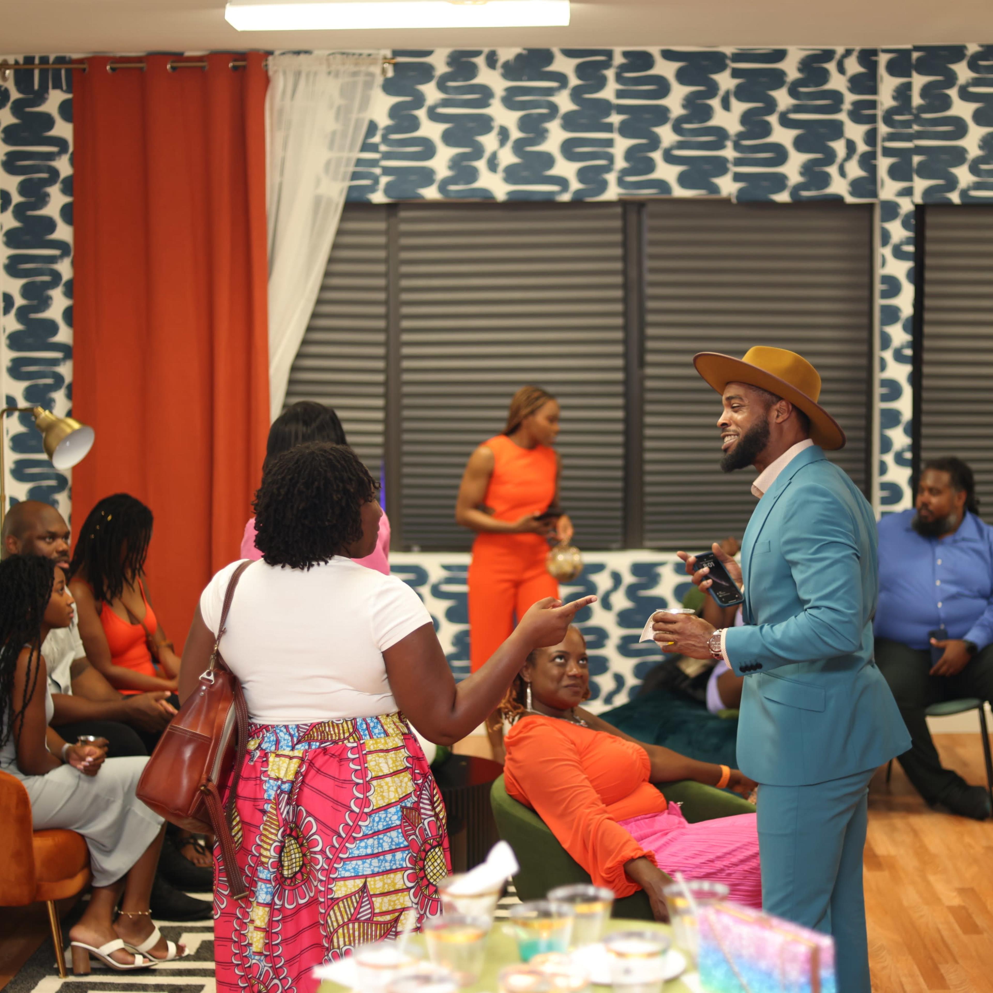 A group of people socialize in a brightly decorated room with patterned walls and colorful furnishings.
