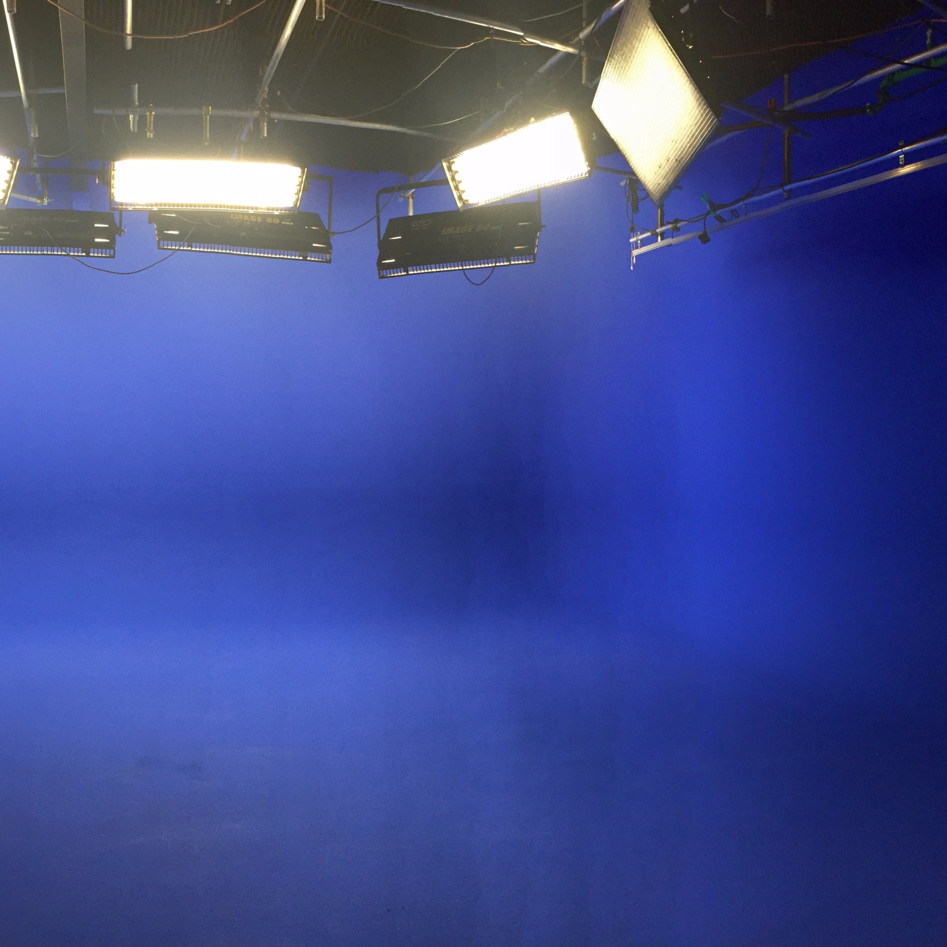 A studio setup with four bright lights positioned above a blue backdrop.