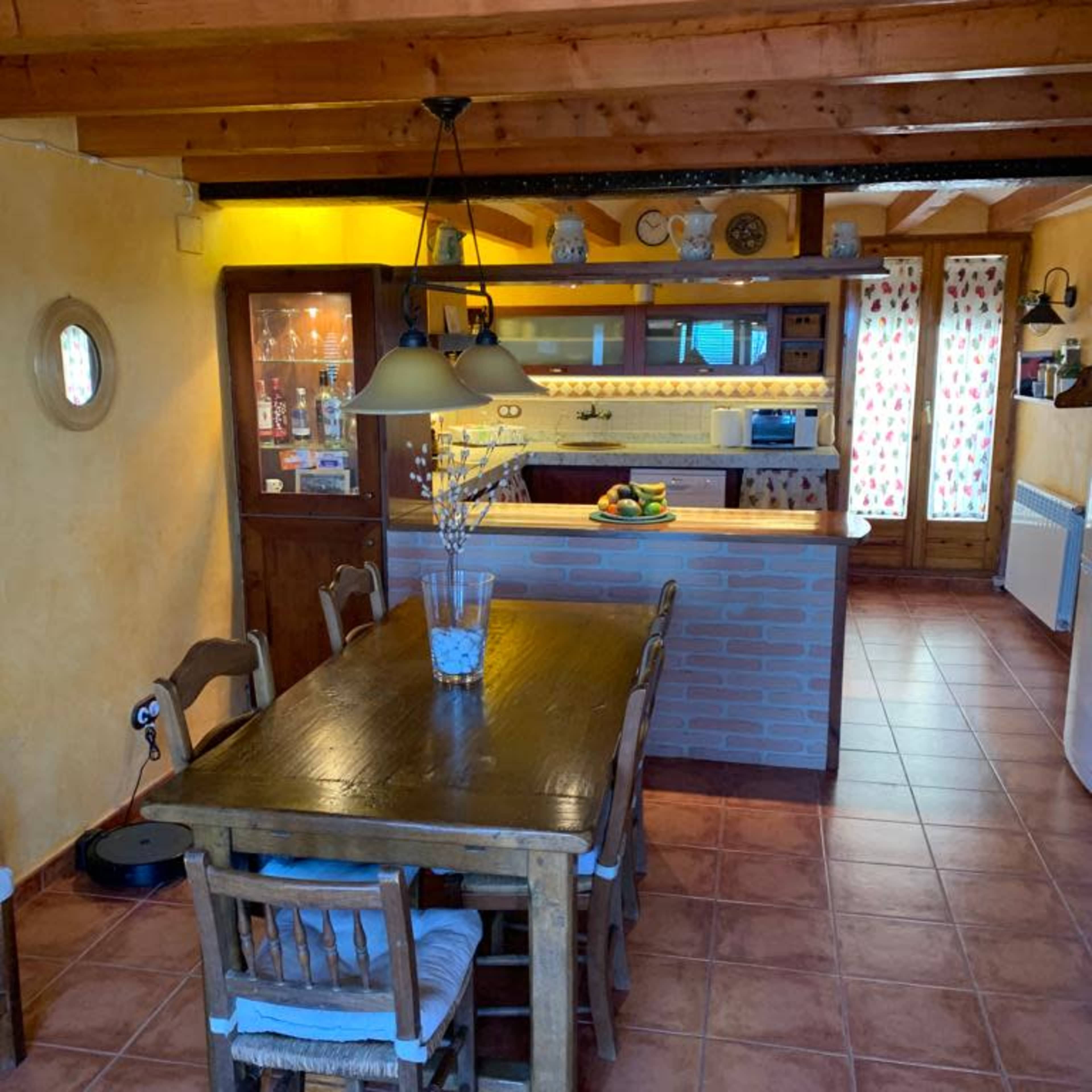 A rustic kitchen and dining area with a wooden table, chairs, and an open layout featuring cabinets and countertop space.