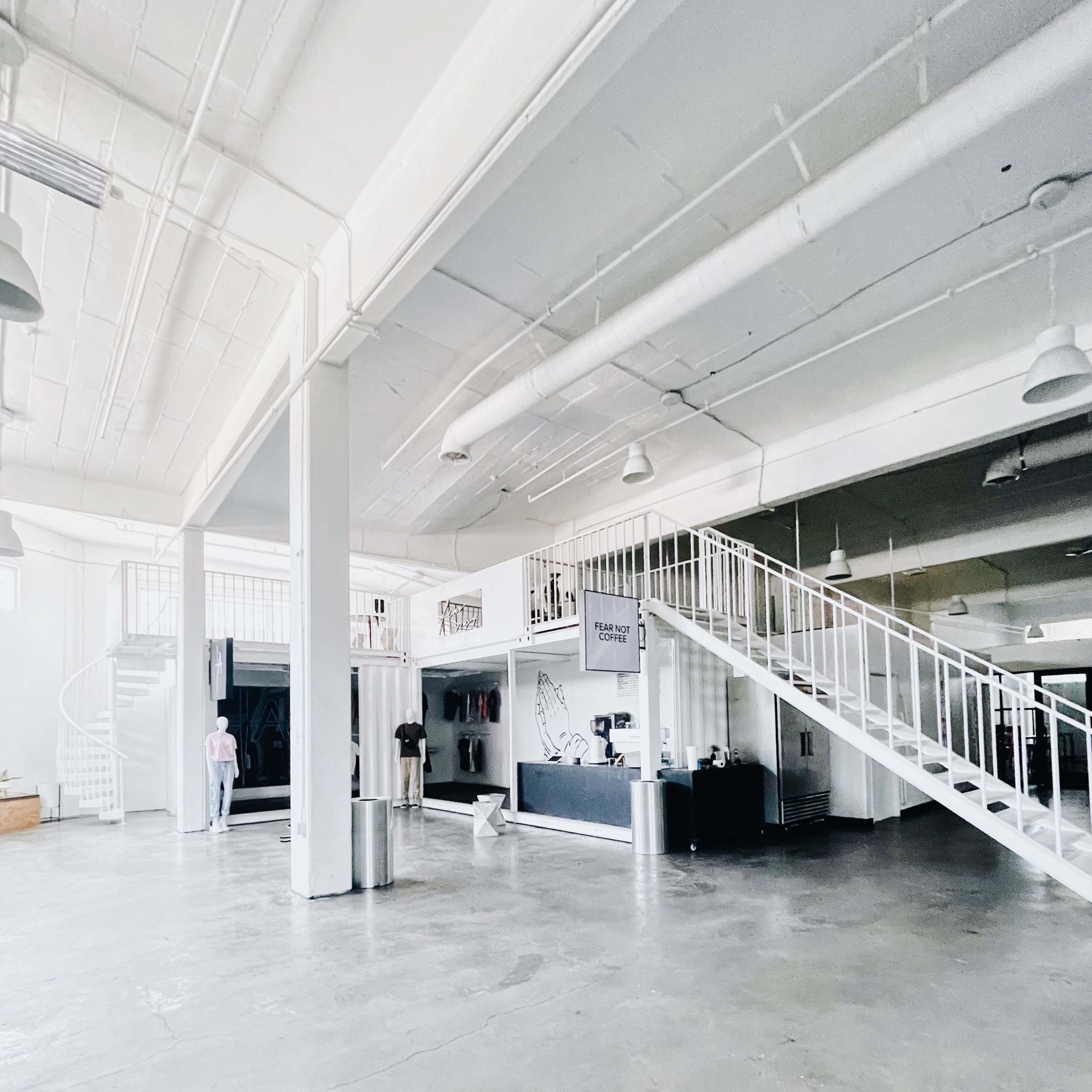 A spacious, open interior of a building featuring a reception area, a staircase, and polished concrete floors.