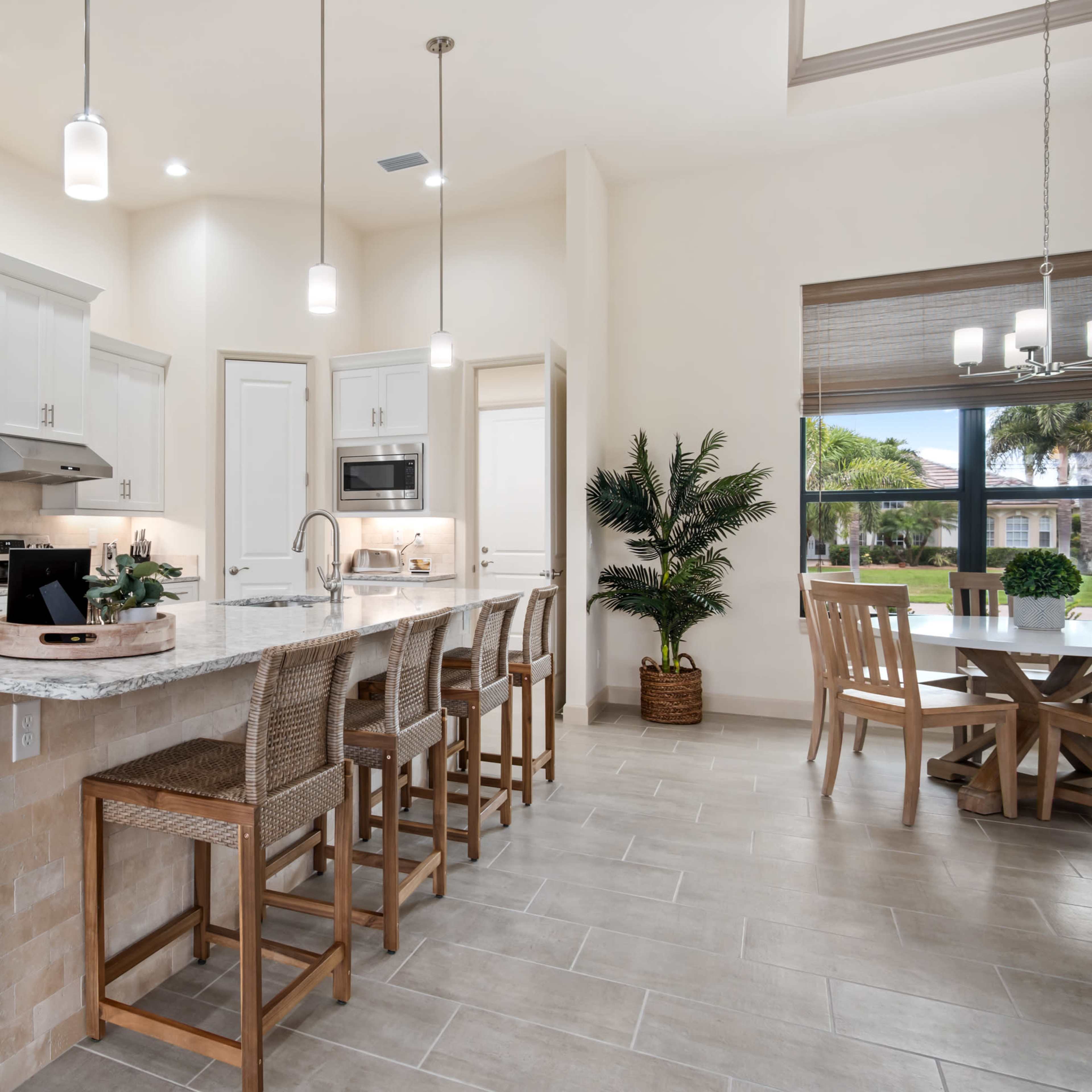 A modern kitchen with a large island, seating for several people, stainless steel appliances, and light-colored cabinetry.