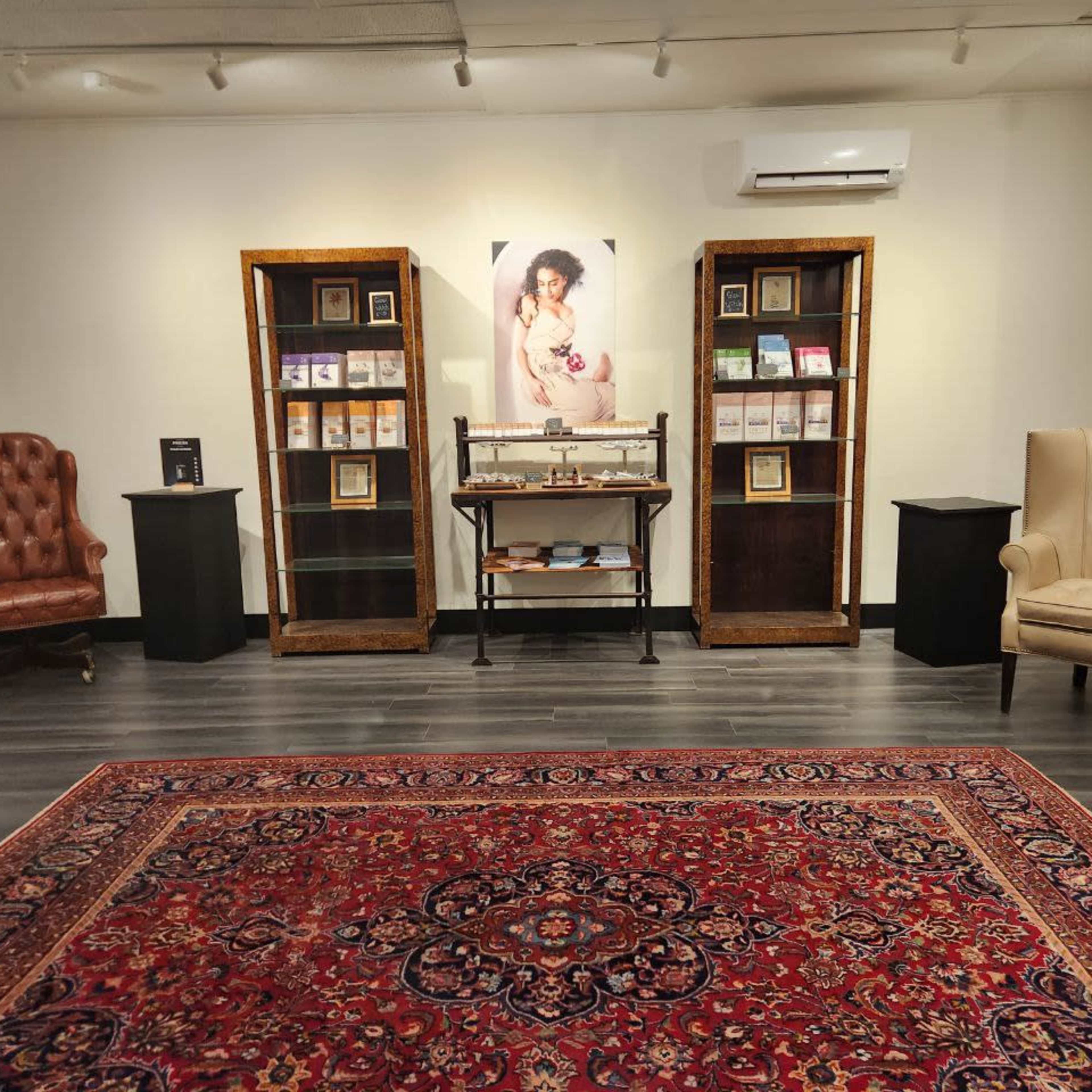 A well-arranged interior space featuring two armchairs, display cases with books, and a prominent portrait on the wall.