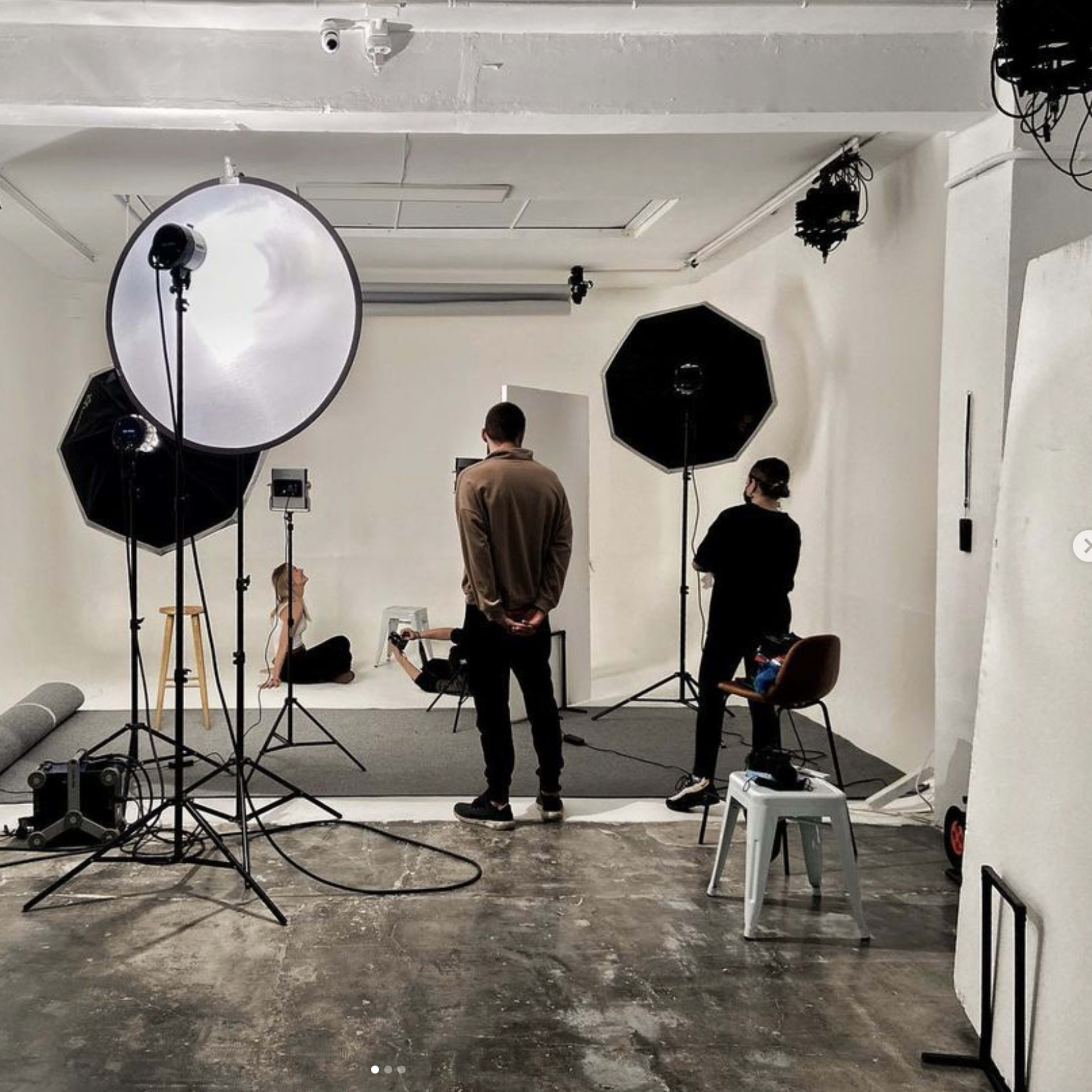 A photography studio is set up with multiple lighting equipment, backdrops, and props arranged for a shoot.