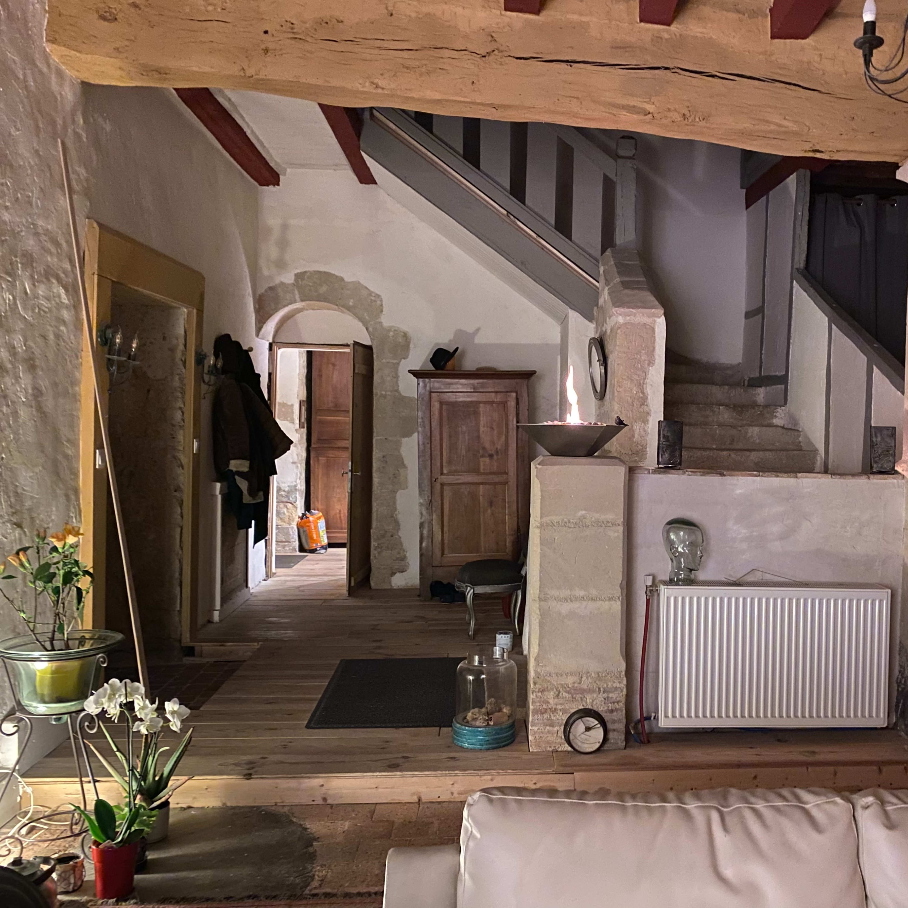 A cozy interior of a home featuring a staircase, wooden floors, and various pieces of furniture.