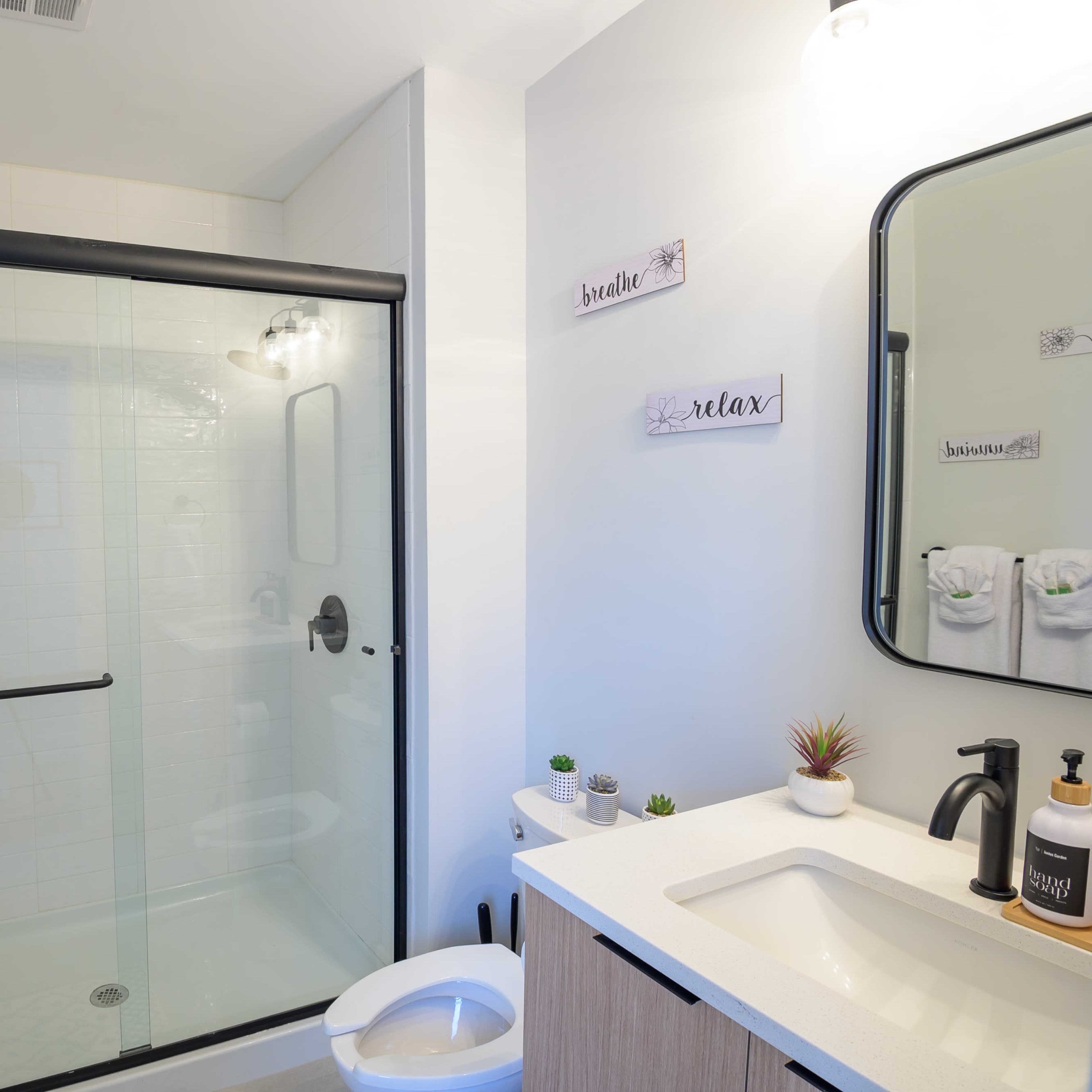 A modern bathroom featuring a glass shower enclosure, a sink with a mirror, and neatly arranged towels.