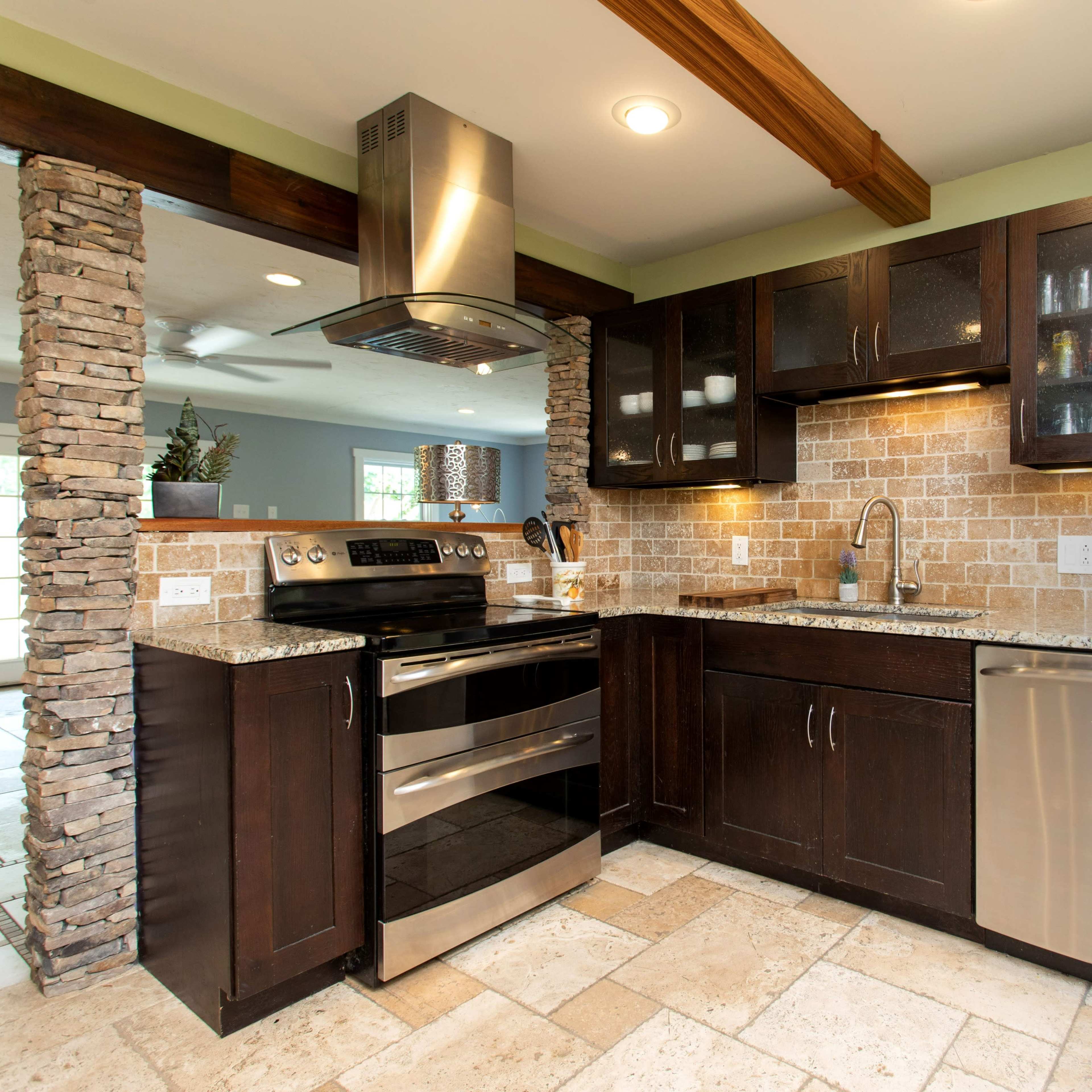 The kitchen features dark wood cabinetry, stainless steel appliances, and a stone accent wall with a tiled backsplash.