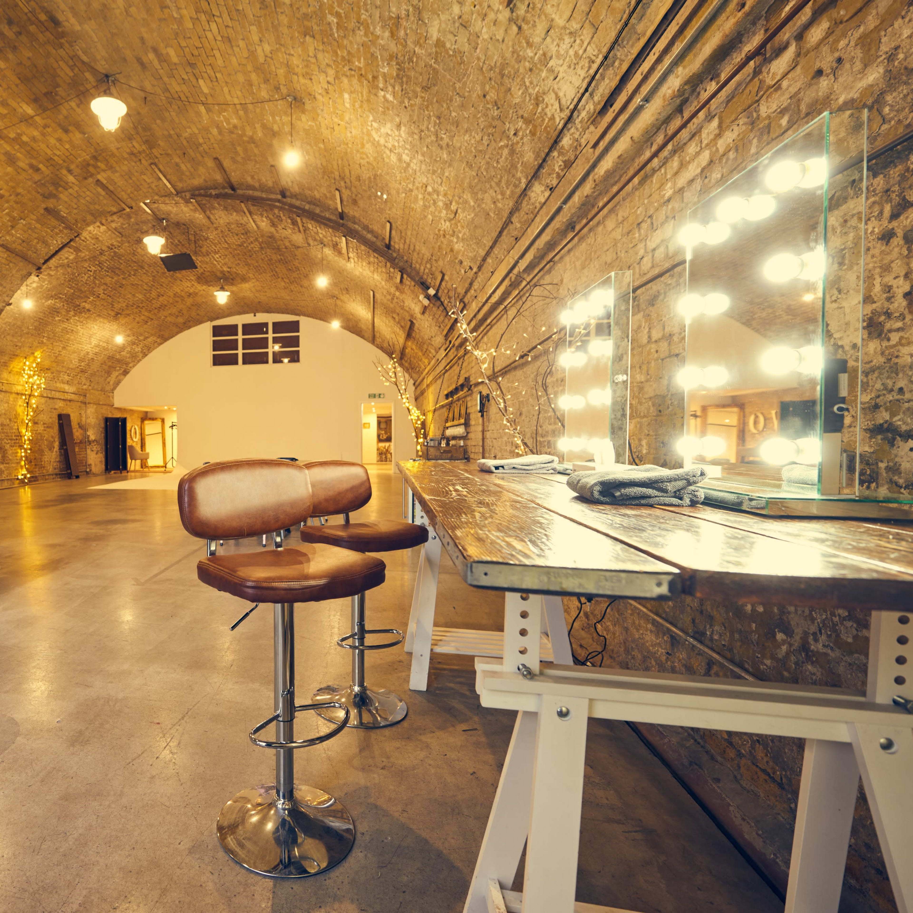 A spacious, arched interior with exposed brick walls, a bar area with tall stools, and soft lighting enhancing the overall ambiance.