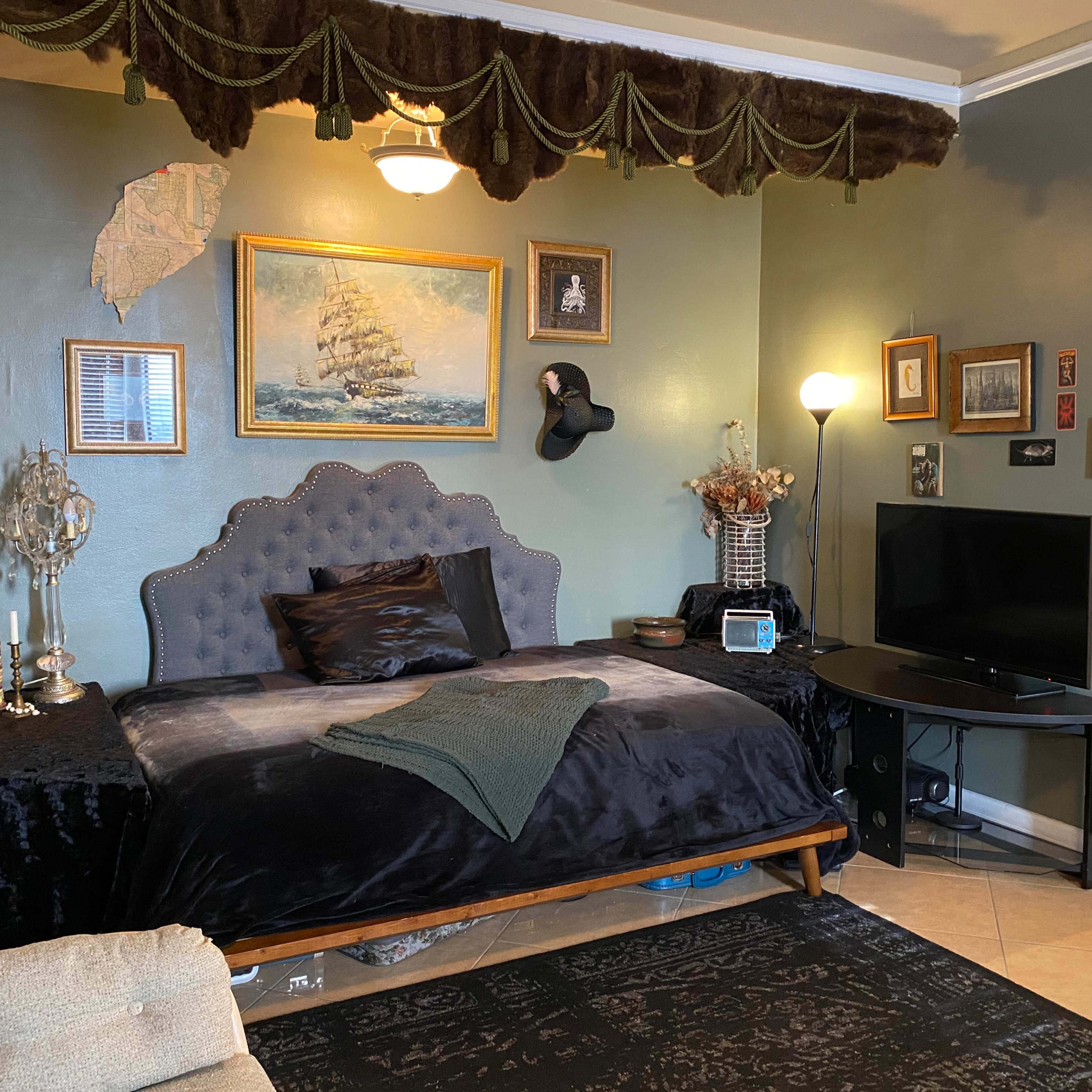 A cozy bedroom with a plush bed, decorative wall art, and a television set against an accent wall.