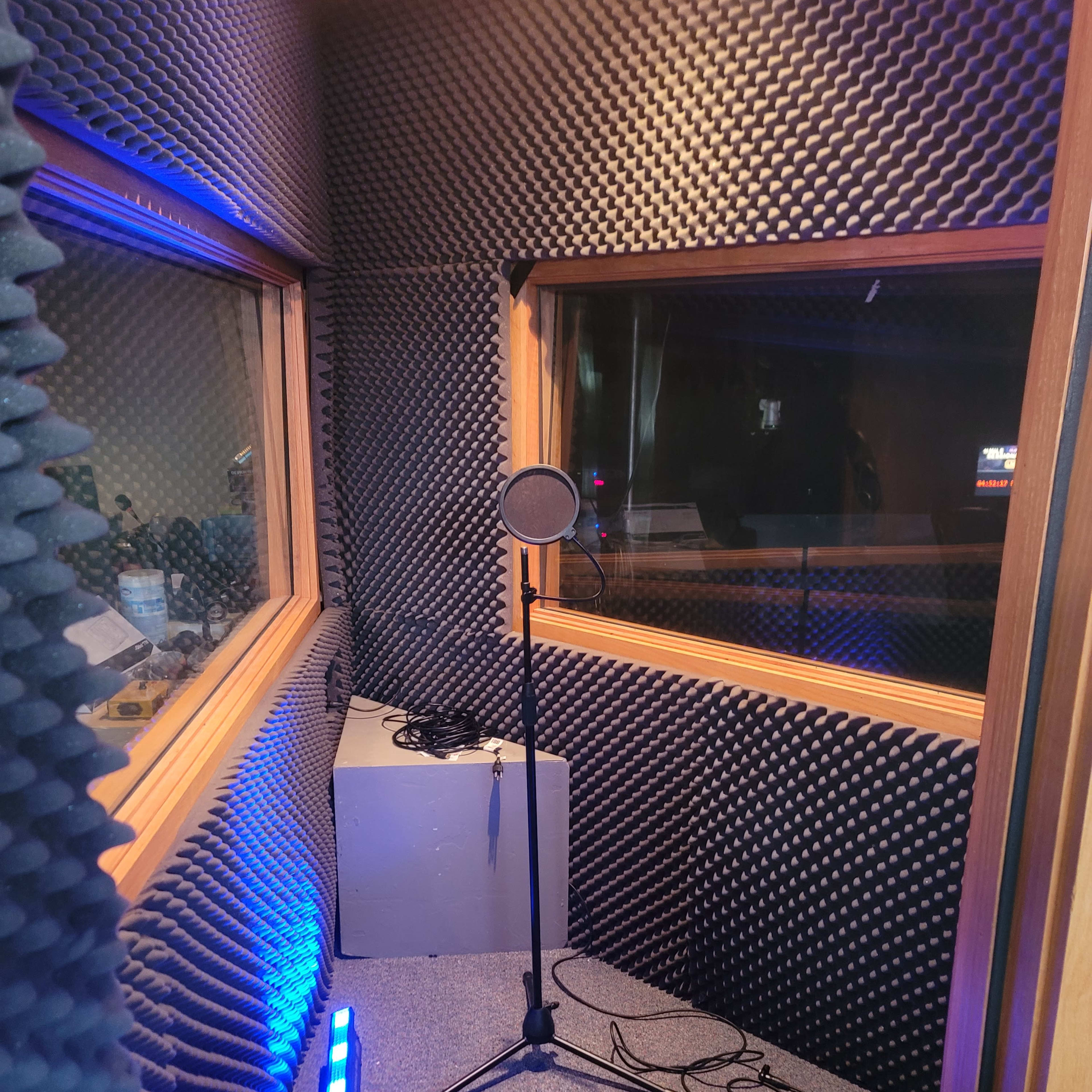 A soundproof recording booth with walls covered in acoustic foam and a microphone on a stand.