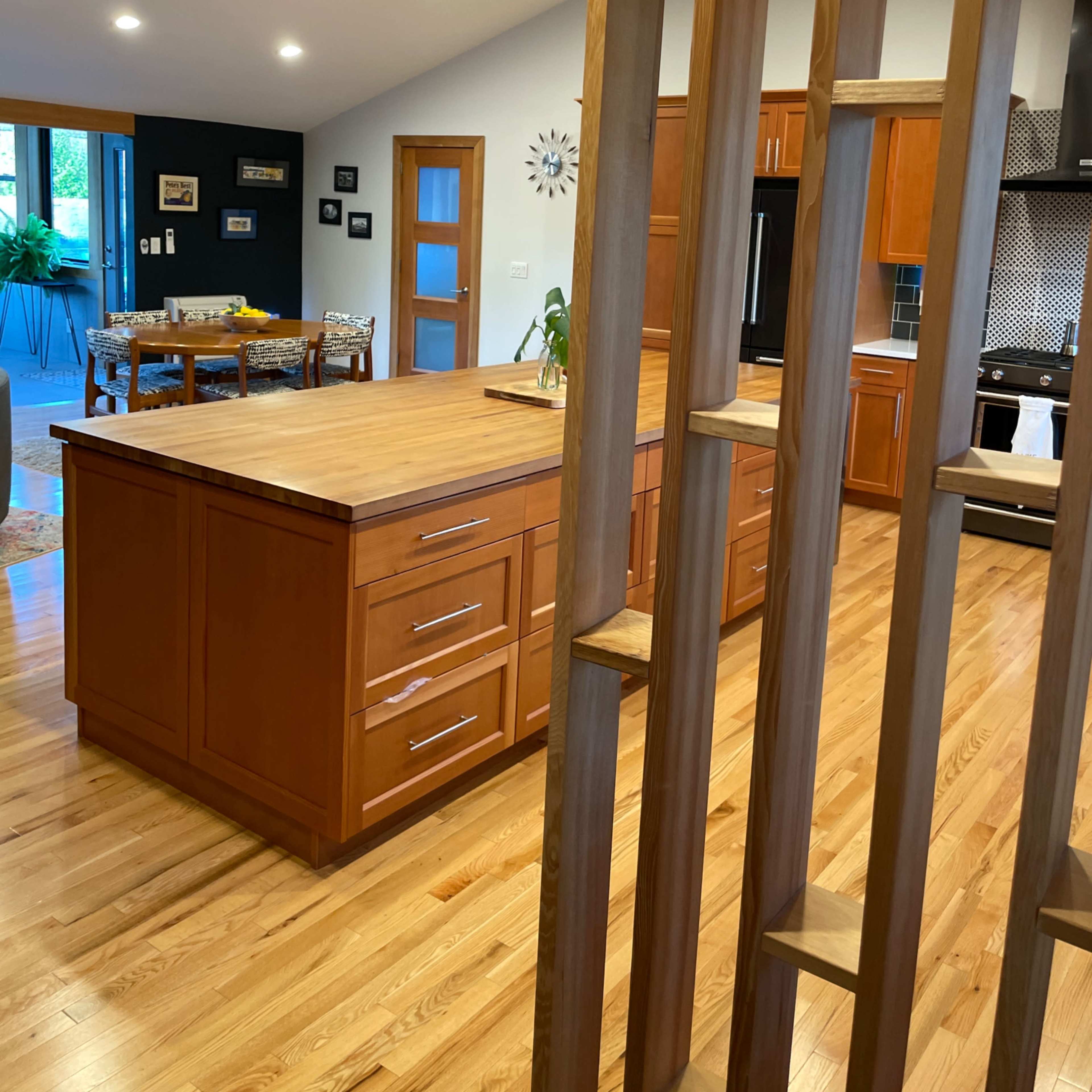 A modern kitchen features a wooden island with drawers and a view of the dining area through a wooden slat partition.