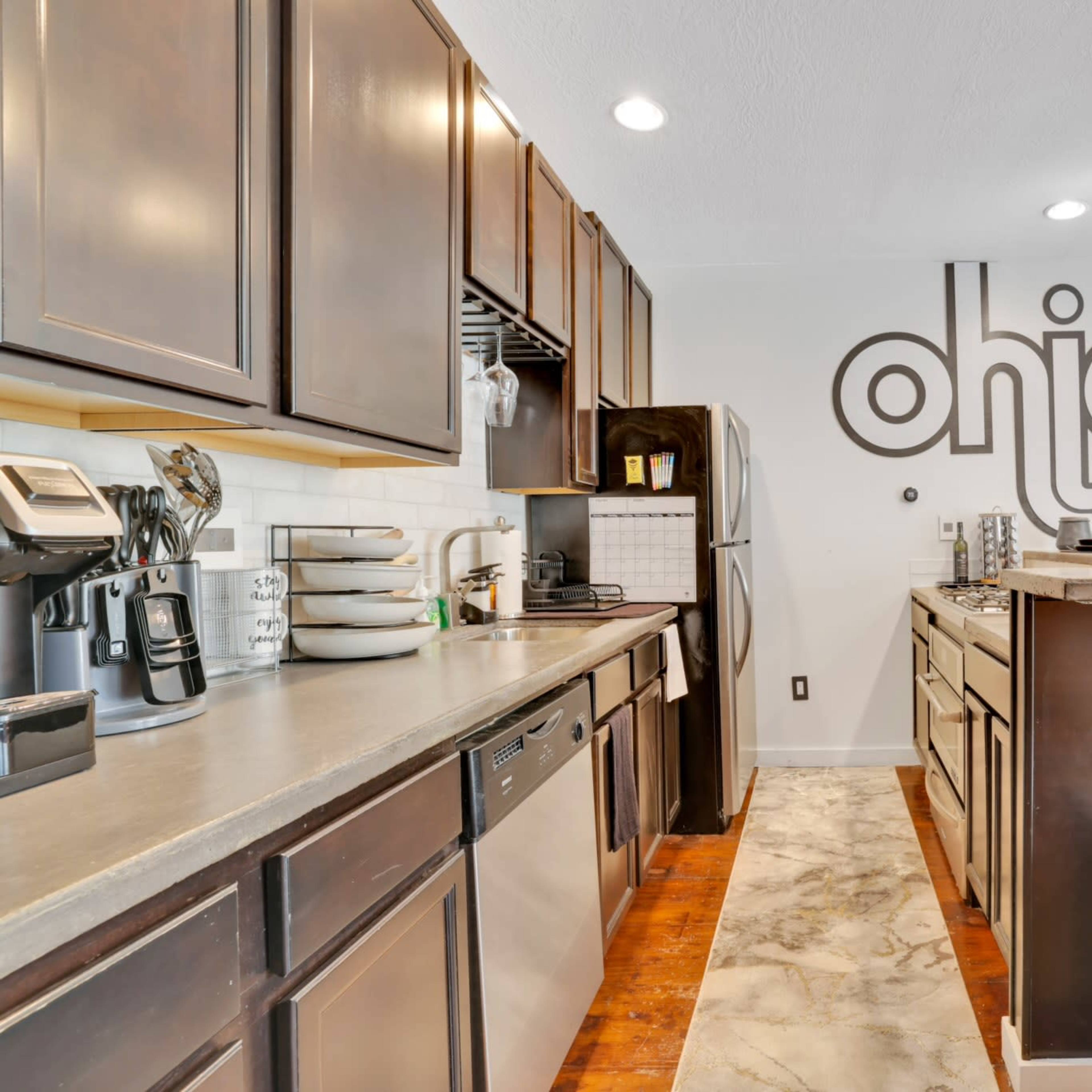A modern kitchen features dark cabinetry, stainless steel appliances, and a decorative "Ohio" wall design.