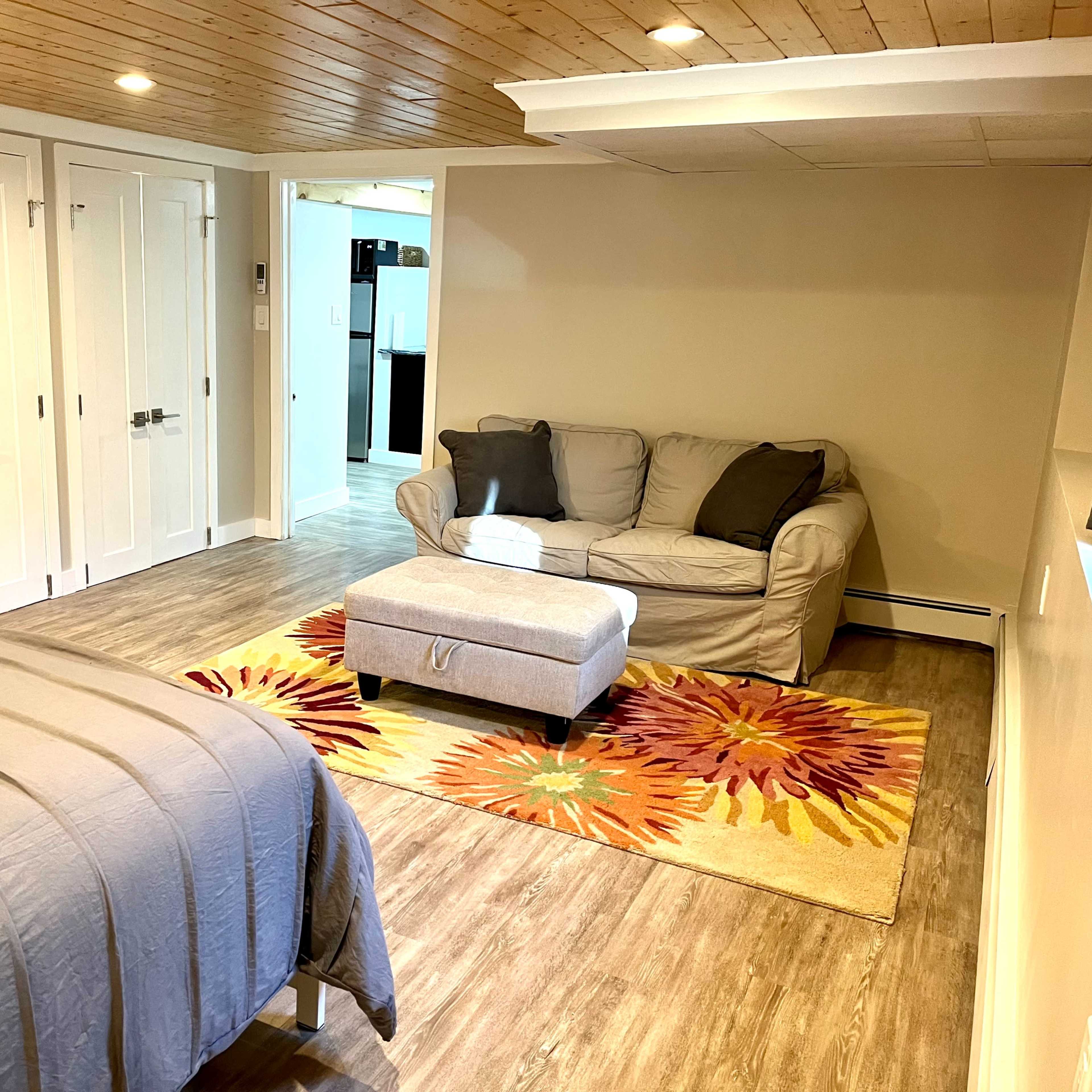 A spacious bedroom featuring a bed, a couch, and a colorful area rug with floral patterns.