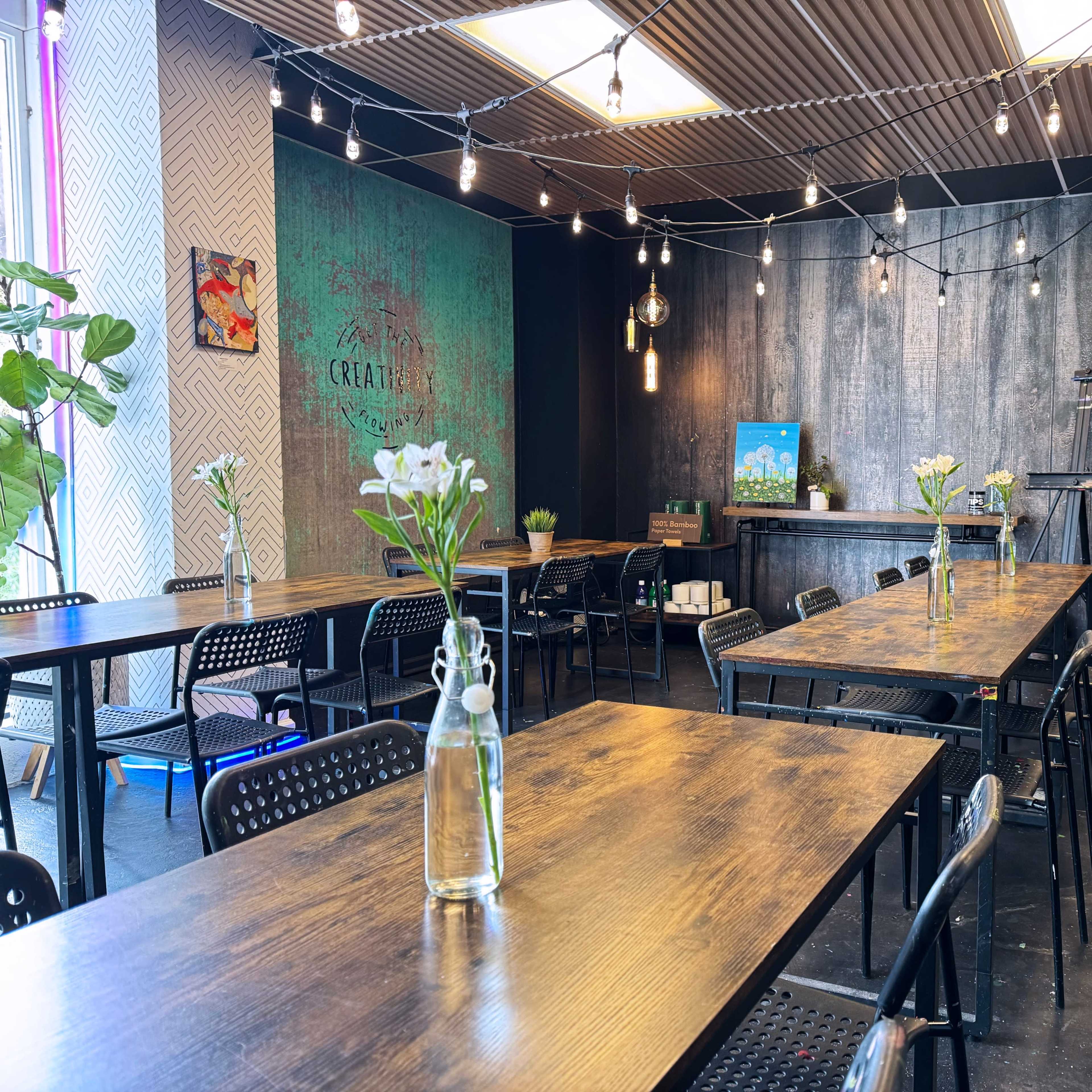 A modern restaurant interior with wooden tables, string lights, and potted plants.