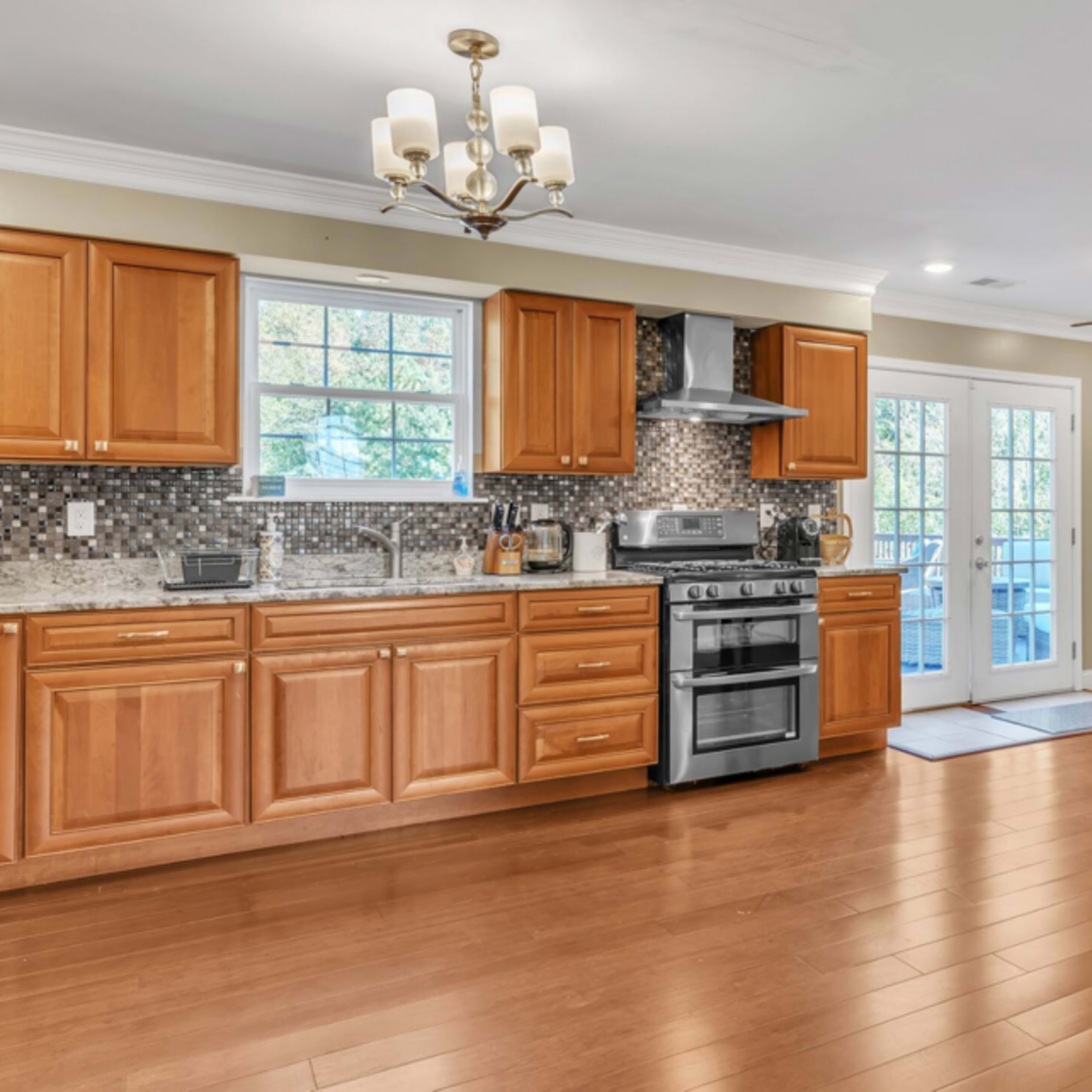 A modern kitchen with wooden cabinetry, stainless steel appliances, and a dining area featuring a table and chairs near a set of French doors.