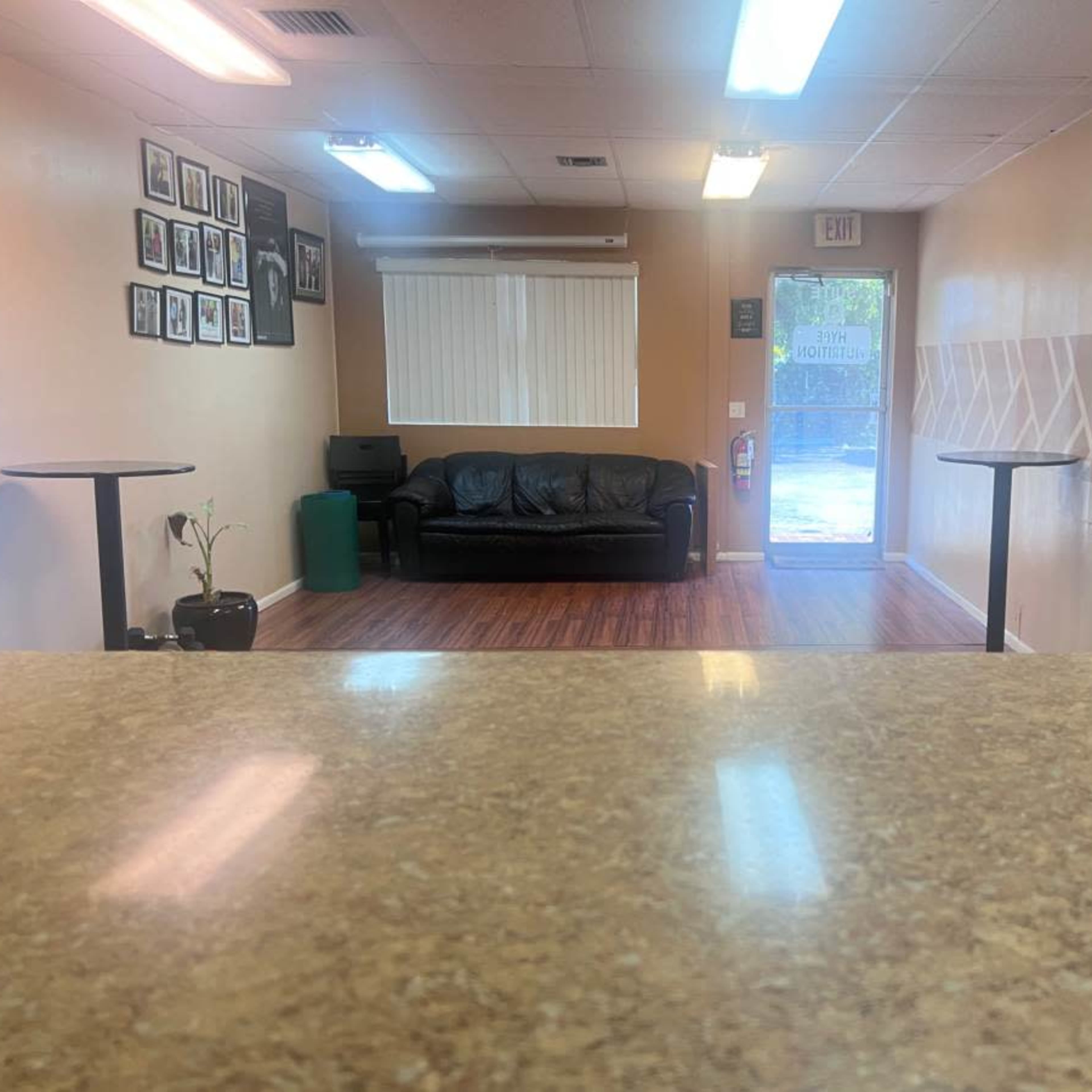 A waiting area with a couch, a green bin, and framed pictures on the wall, viewed from a counter.
