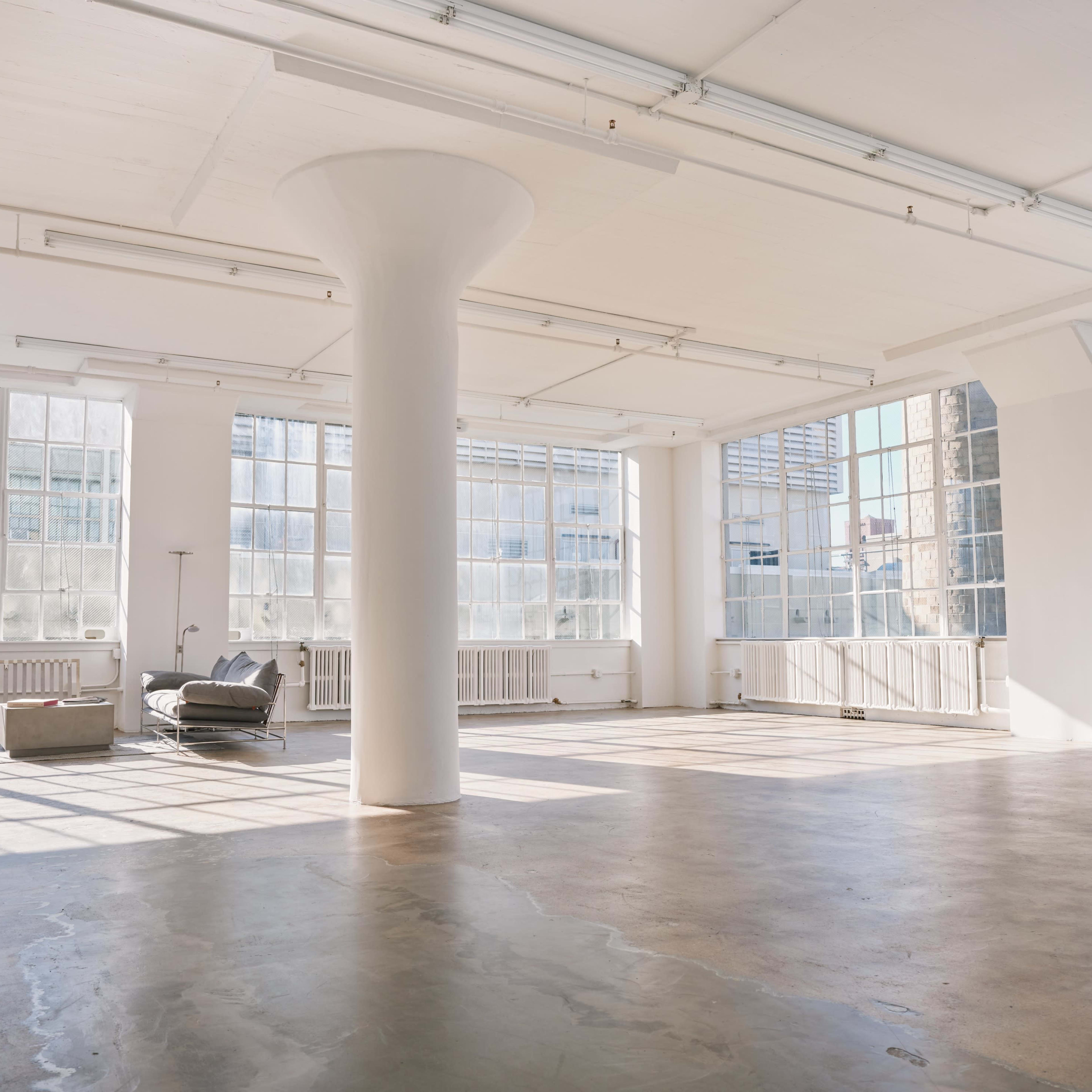 A spacious, well-lit interior features large windows and a concrete floor.