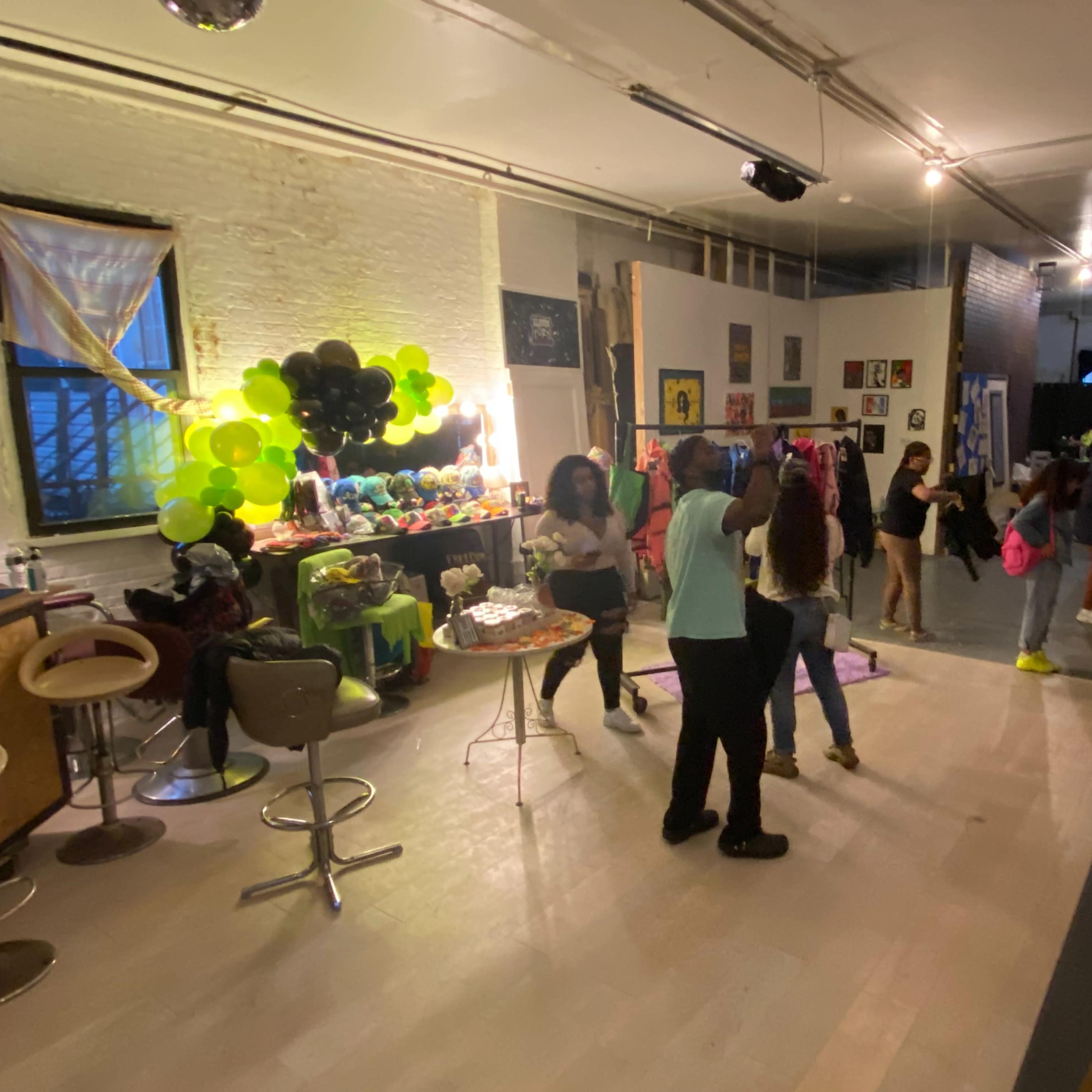 A lively gathering is taking place in a spacious indoor venue, featuring colorful decorations and groups of people socializing and dancing.
