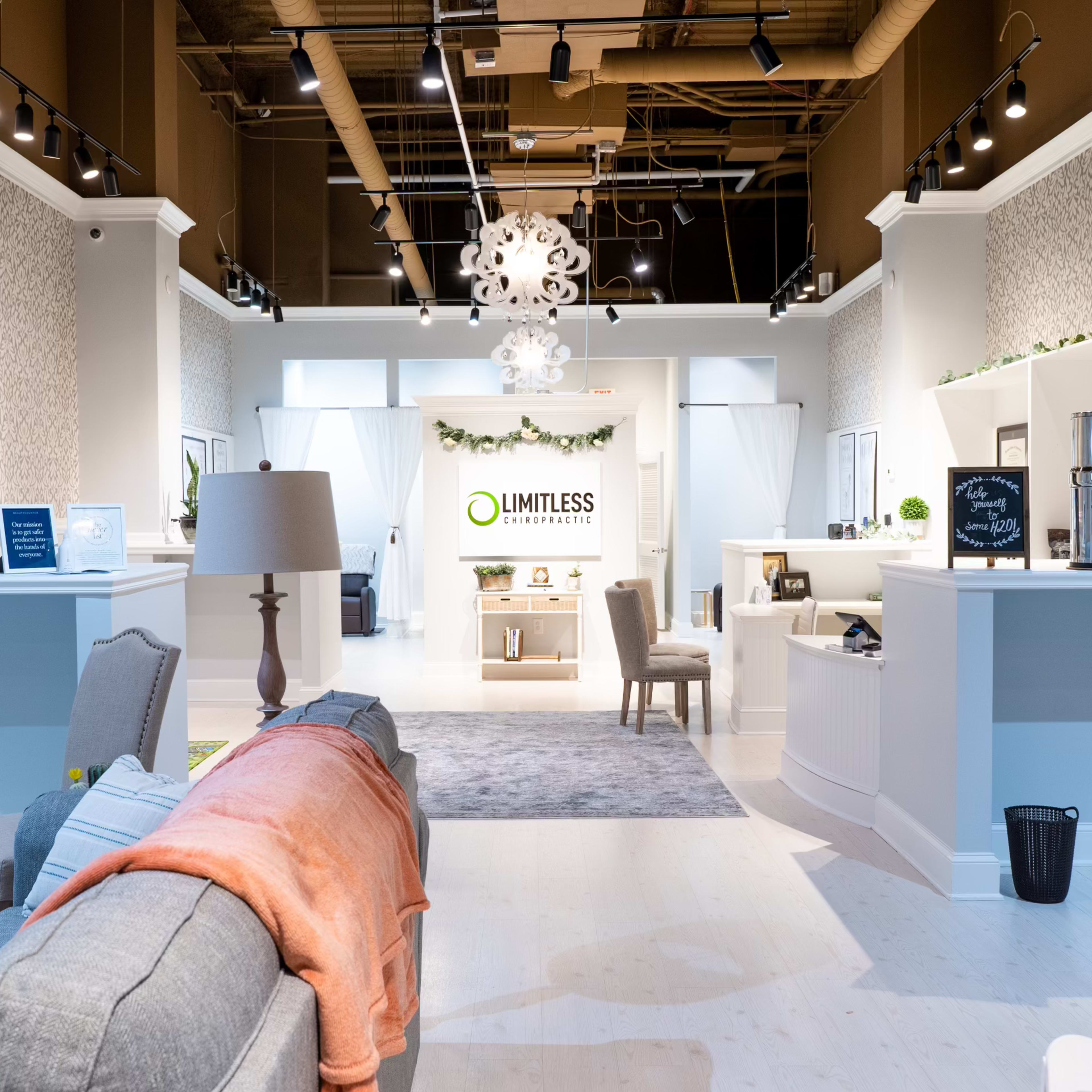 A modern interior design studio with white walls, a gray sofa, and a central display area featuring the logo "LIMITLESS" against a backdrop of decorative elements.