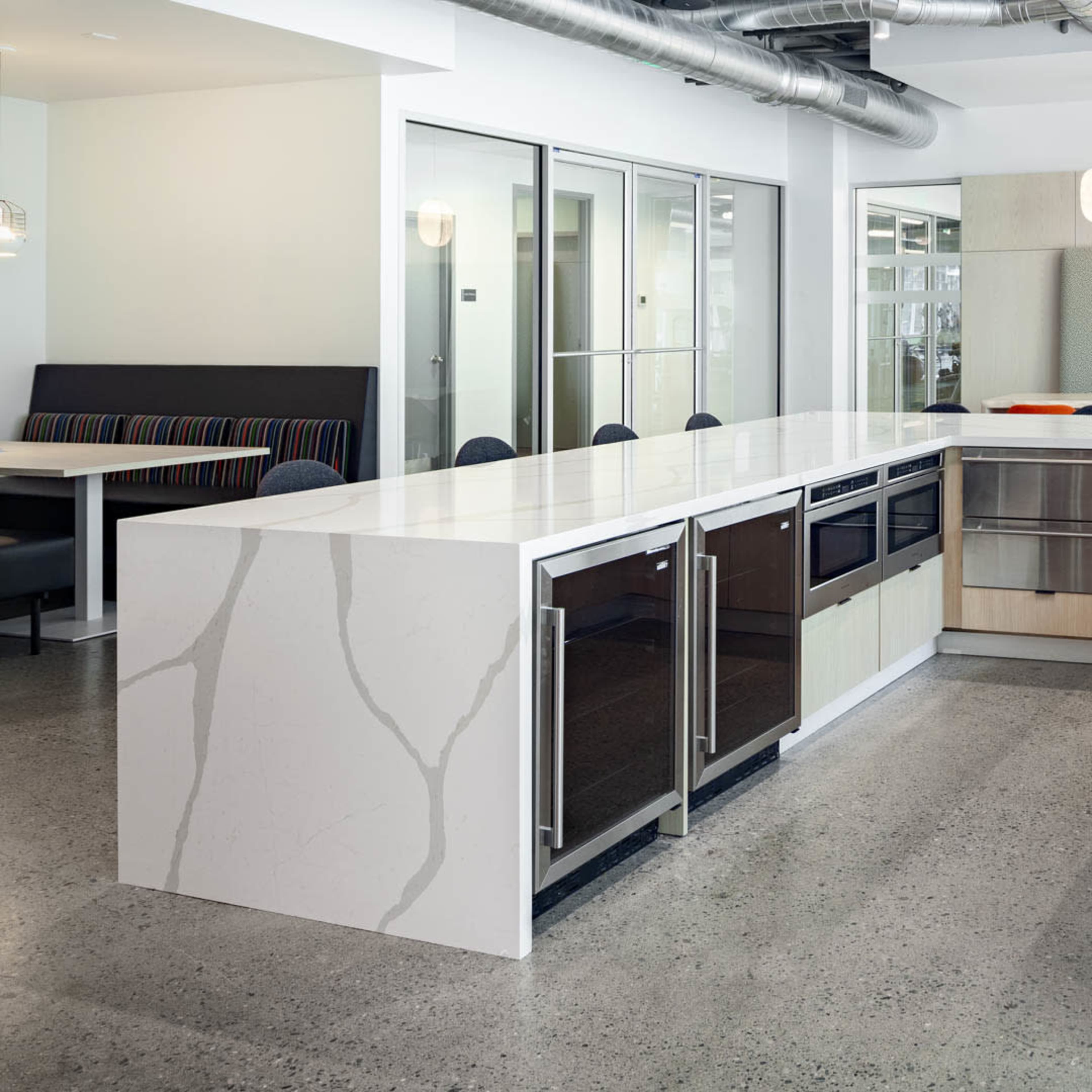 A modern kitchen with a large island, equipped with sleek cabinetry, a sink, and stainless steel appliances.