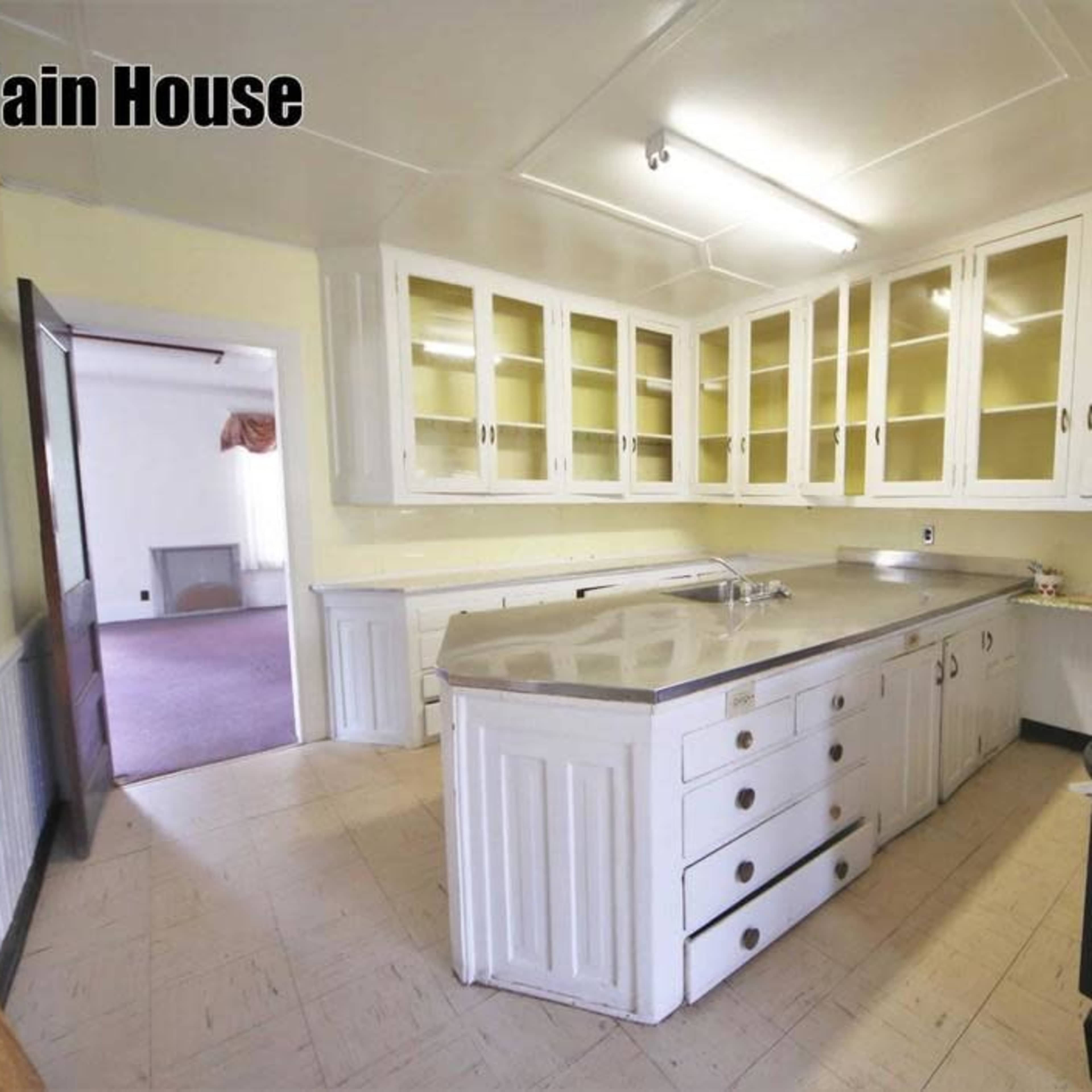 A spacious kitchen with white cabinetry and a large central island, featuring a gas stove against the wall.