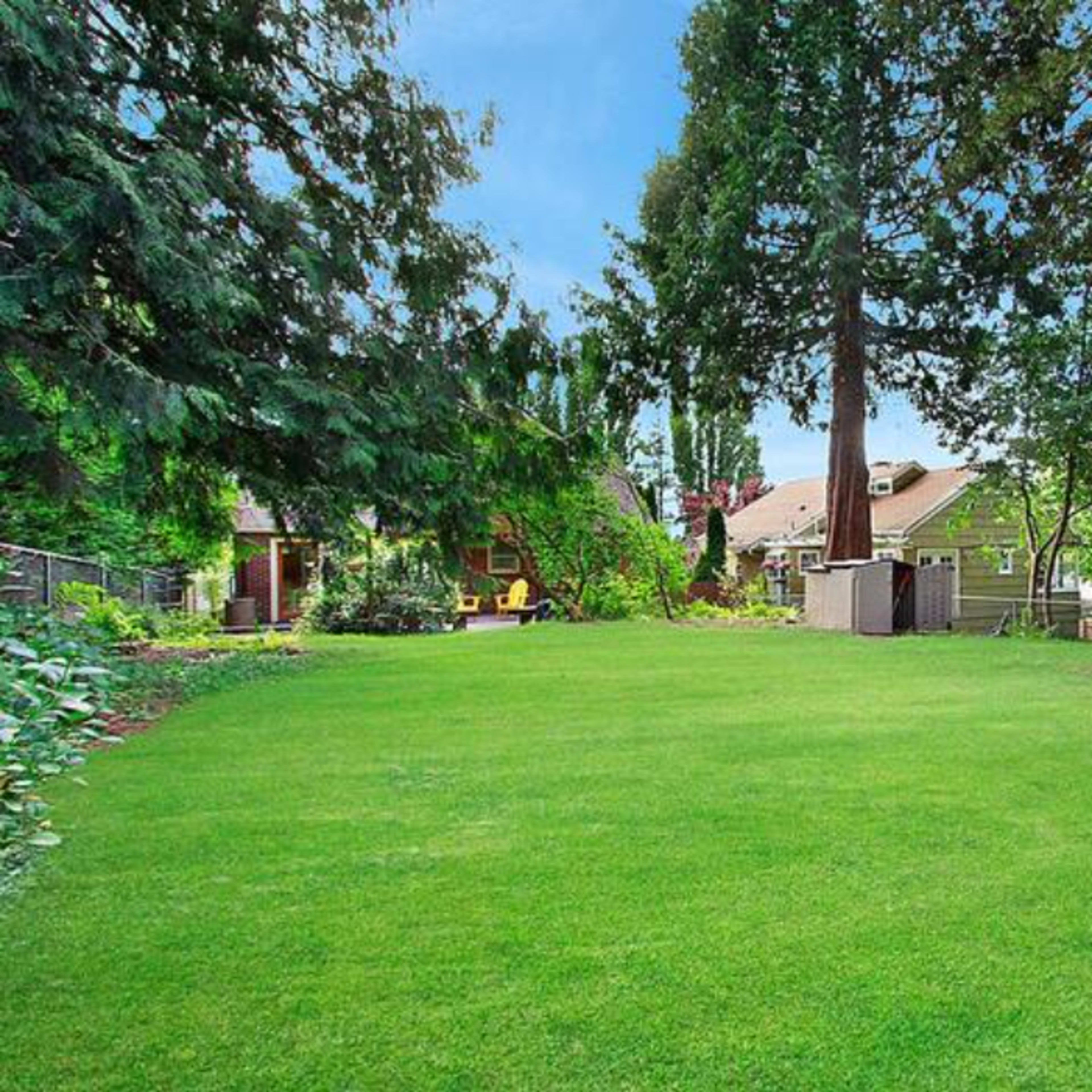 A spacious green lawn surrounded by trees and a few houses in a residential area.
