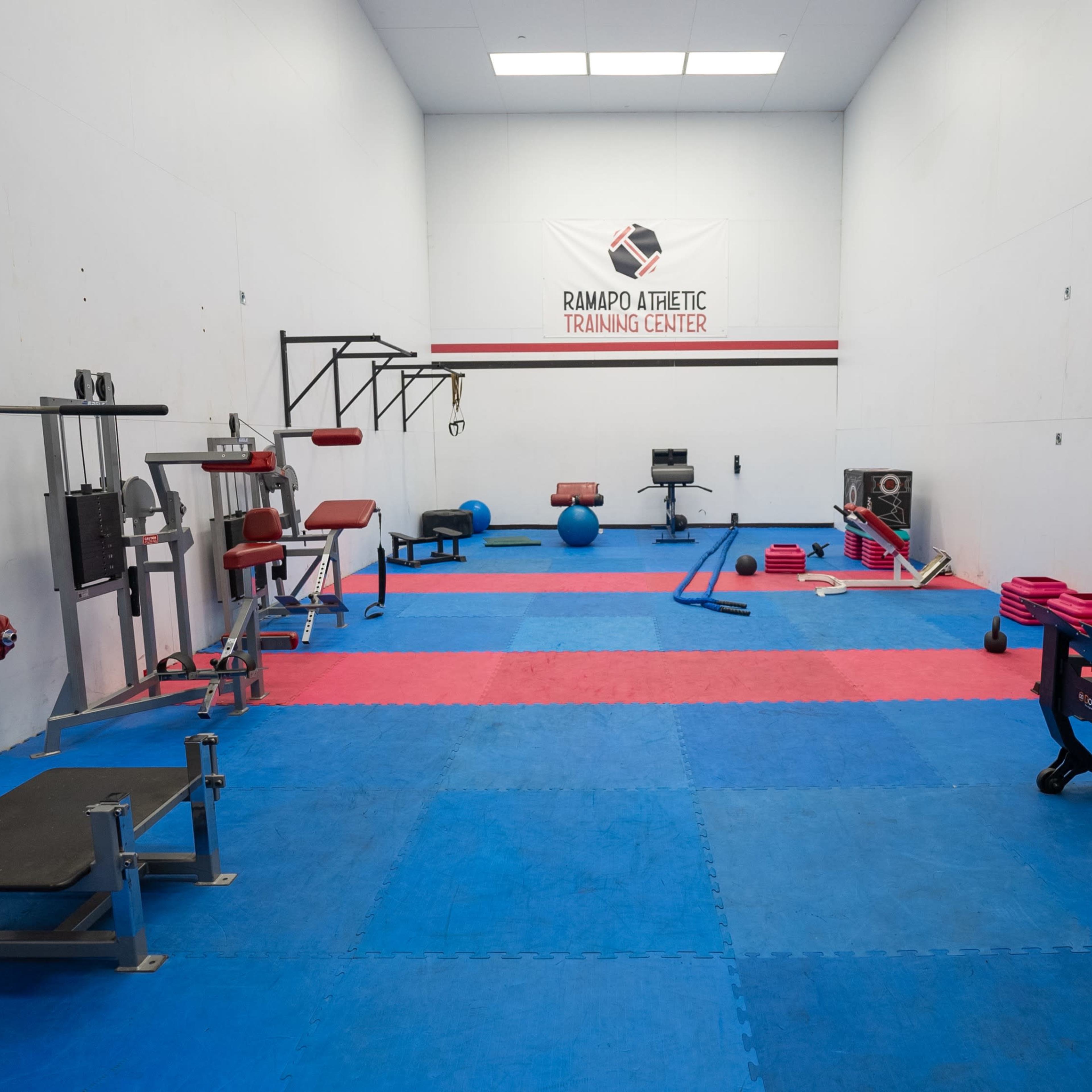 A fitness training center with various gym equipment organized on blue rubber flooring.