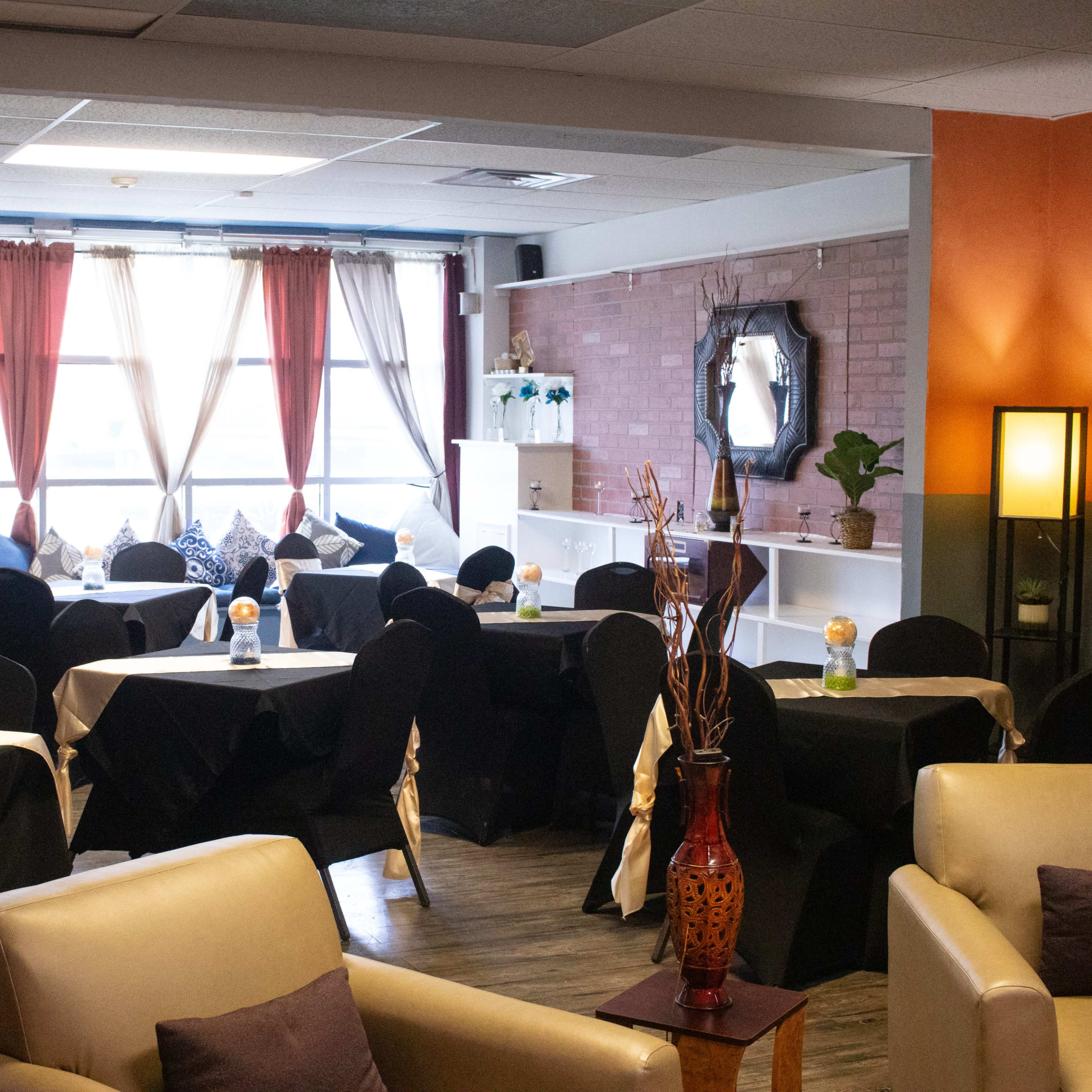 A cozy dining area with black tablecloths and illuminated centerpieces positioned around neatly arranged tables.