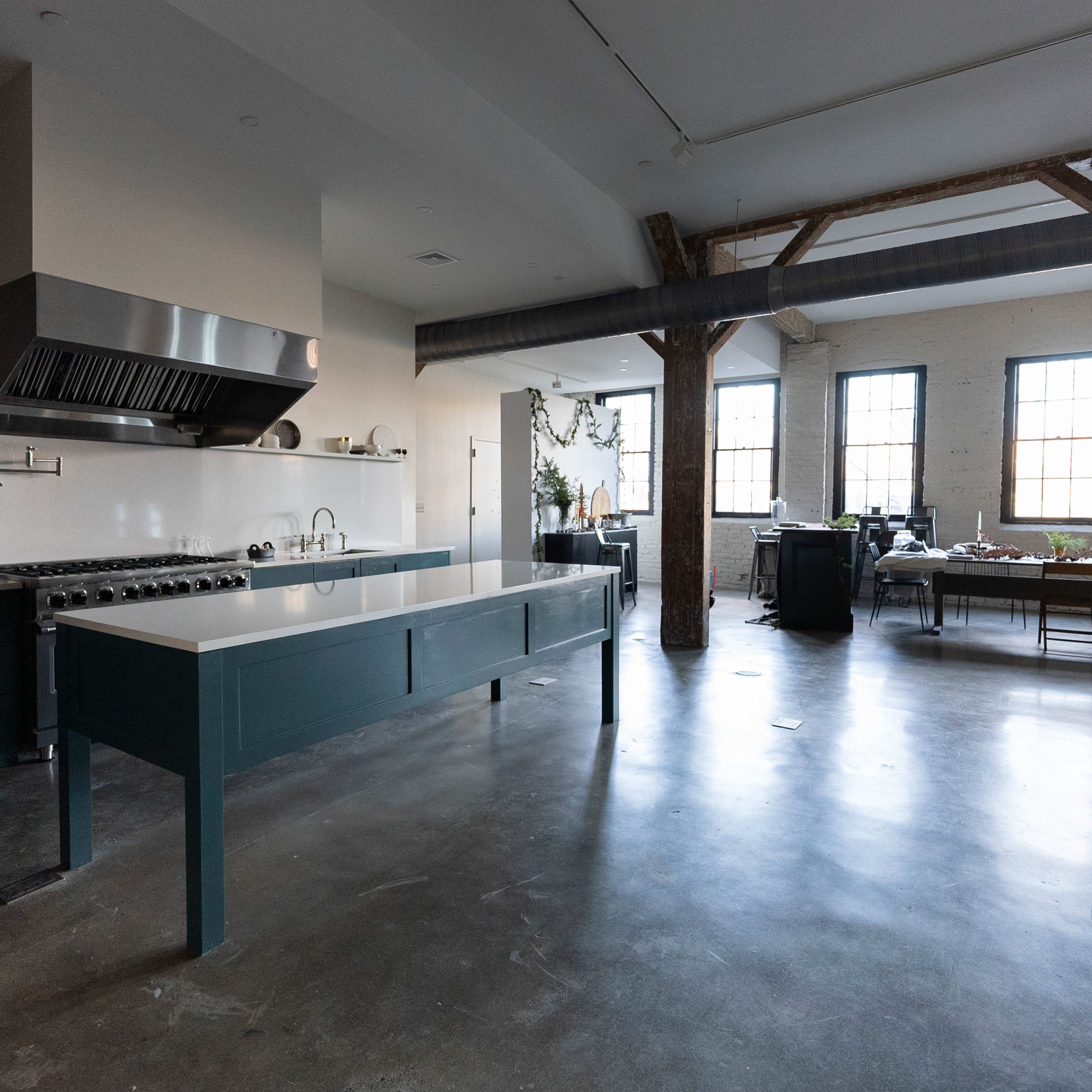 A modern kitchen featuring a large central island, stainless steel appliances, and large windows with natural light illuminating the space.