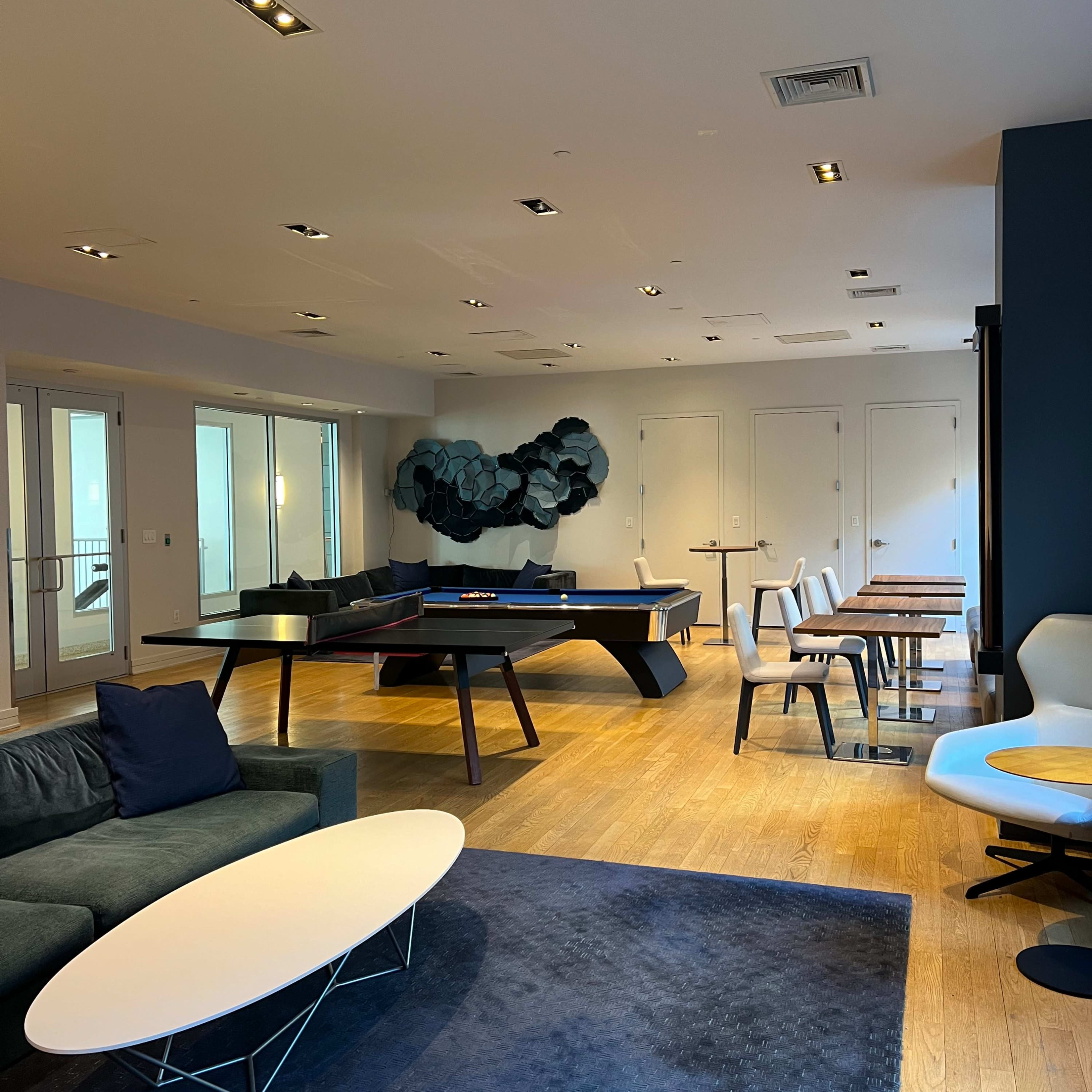 A modern lounge area features stylish seating, a central coffee table, and various tables arranged throughout the space.