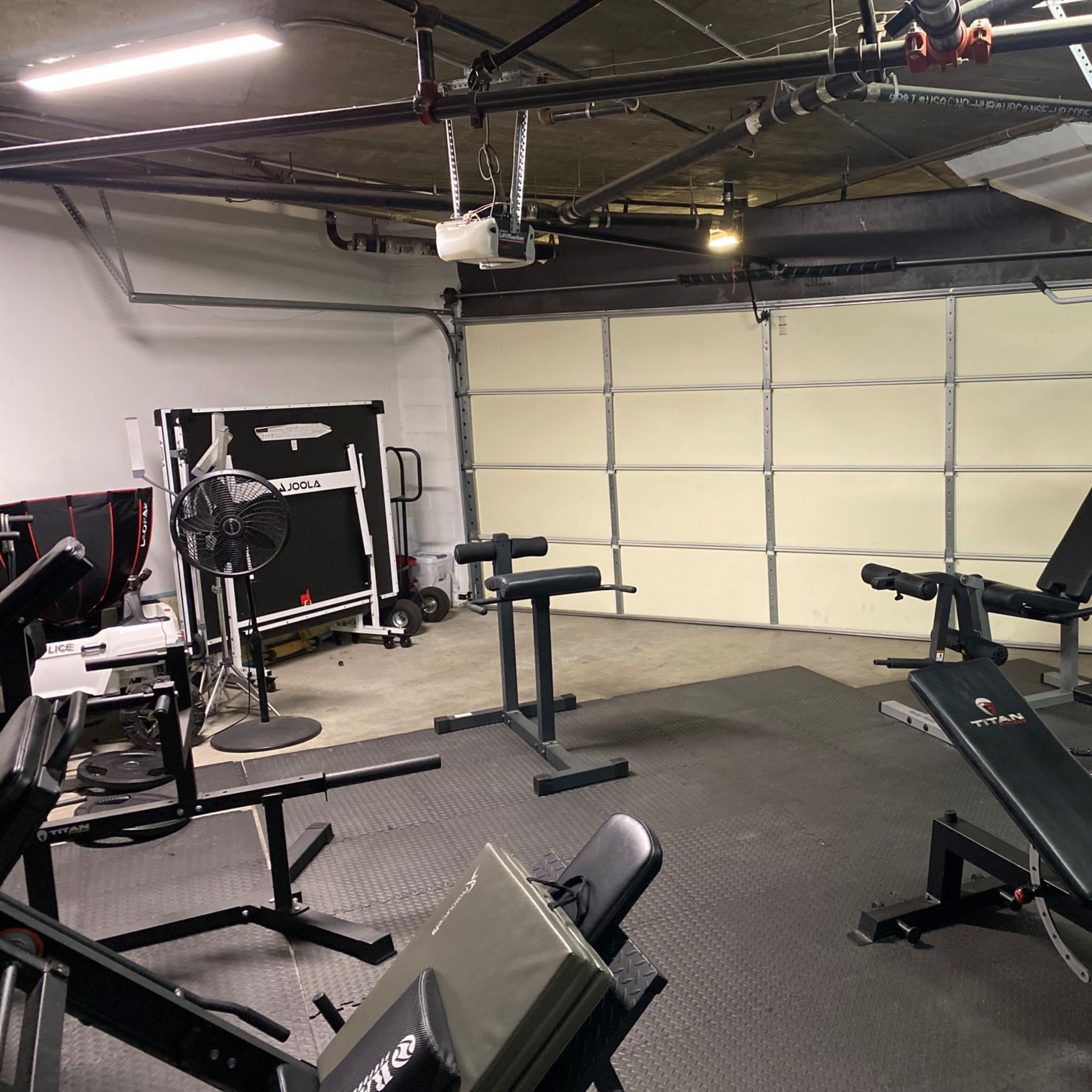 A home gym equipped with various workout machines and weights in a garage space.
