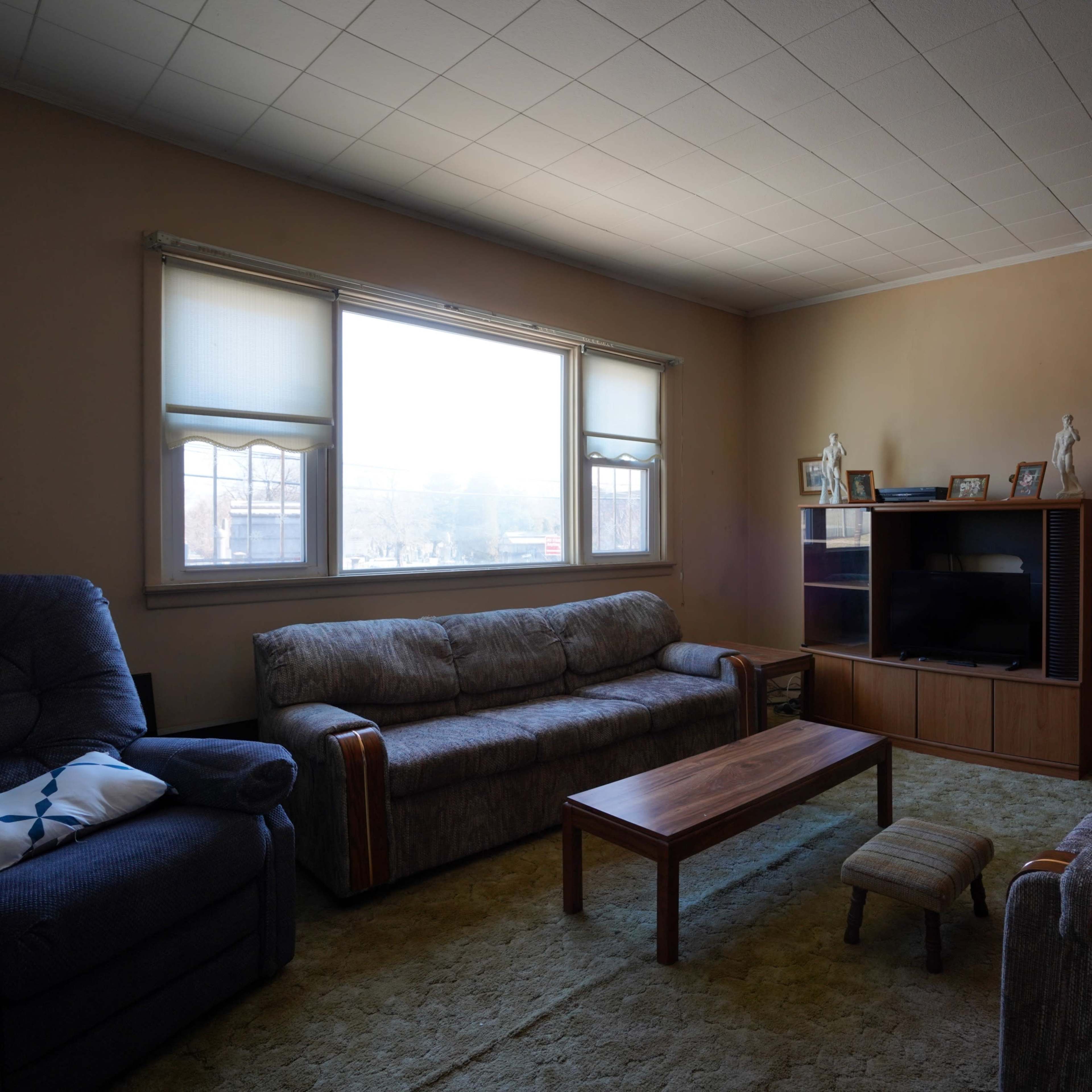 A sparsely furnished living room with two sofas, a coffee table, and a television unit against a wall.
