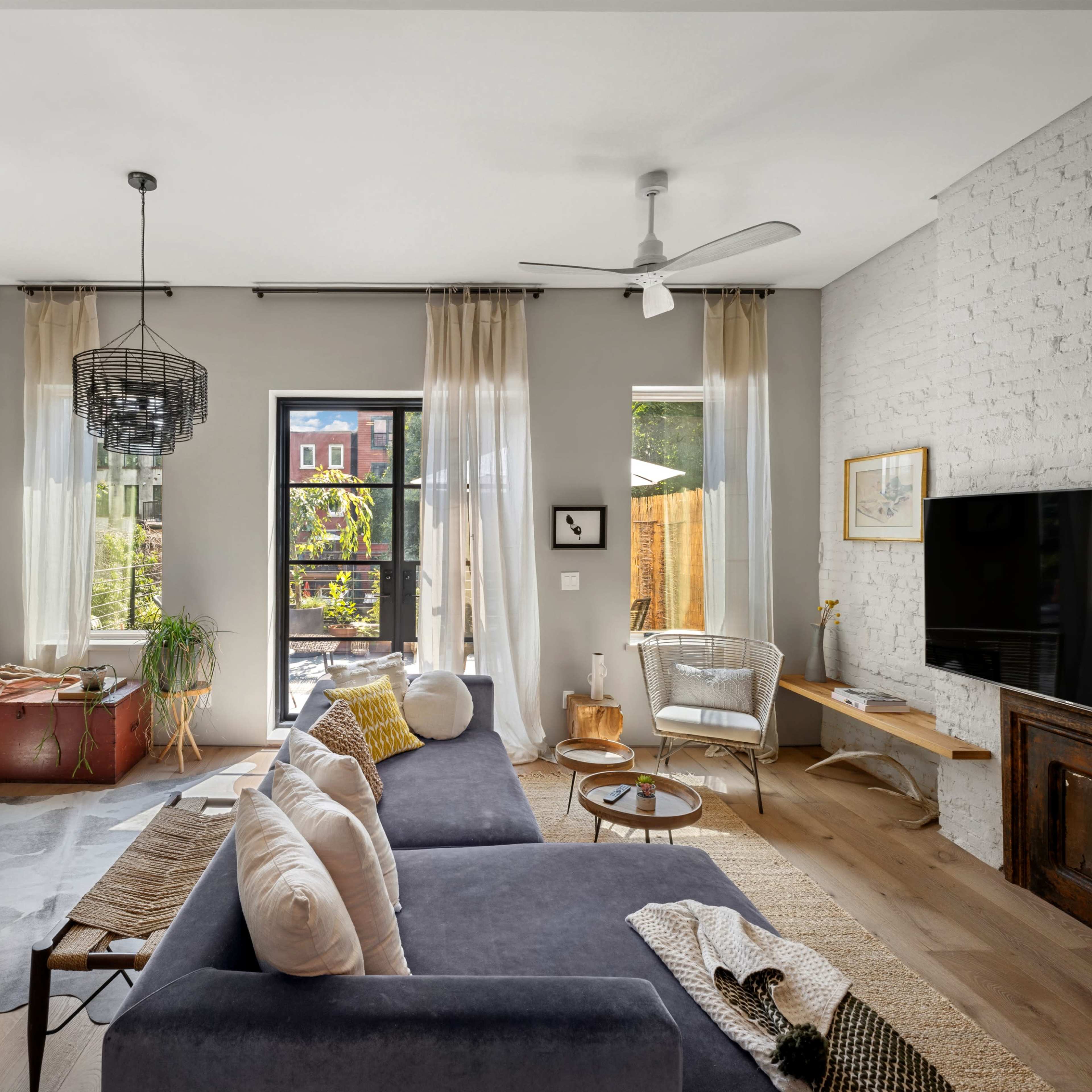 A modern living room featuring a gray sofa, a wooden coffee table, and large windows that allow natural light to illuminate the space.