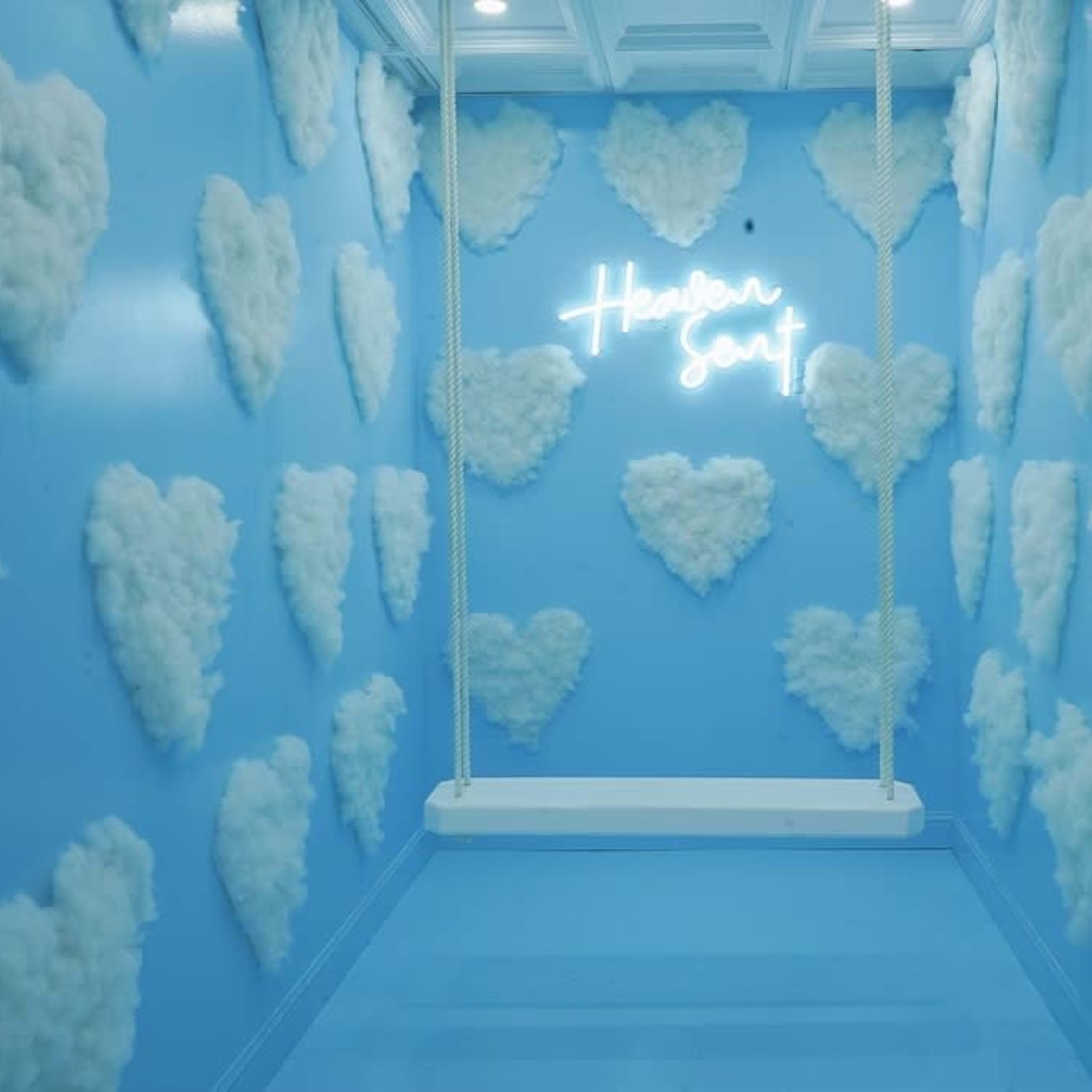 A blue room with heart-shaped cloud decorations on the walls and a swing hanging from the ceiling.