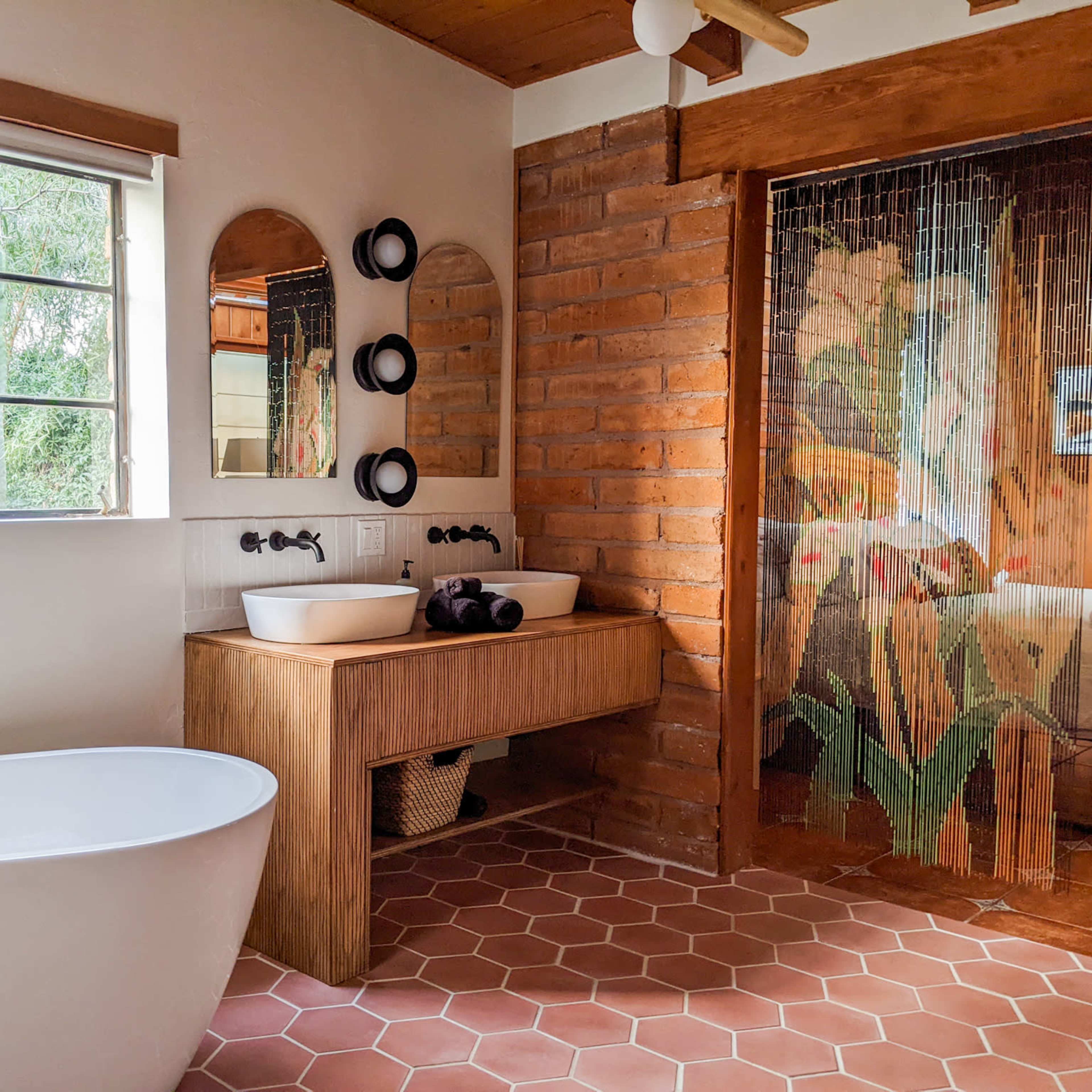 The scene features a modern bathroom with a freestanding bathtub, dual sinks on a wooden vanity, and a glass door adorned with a floral design.