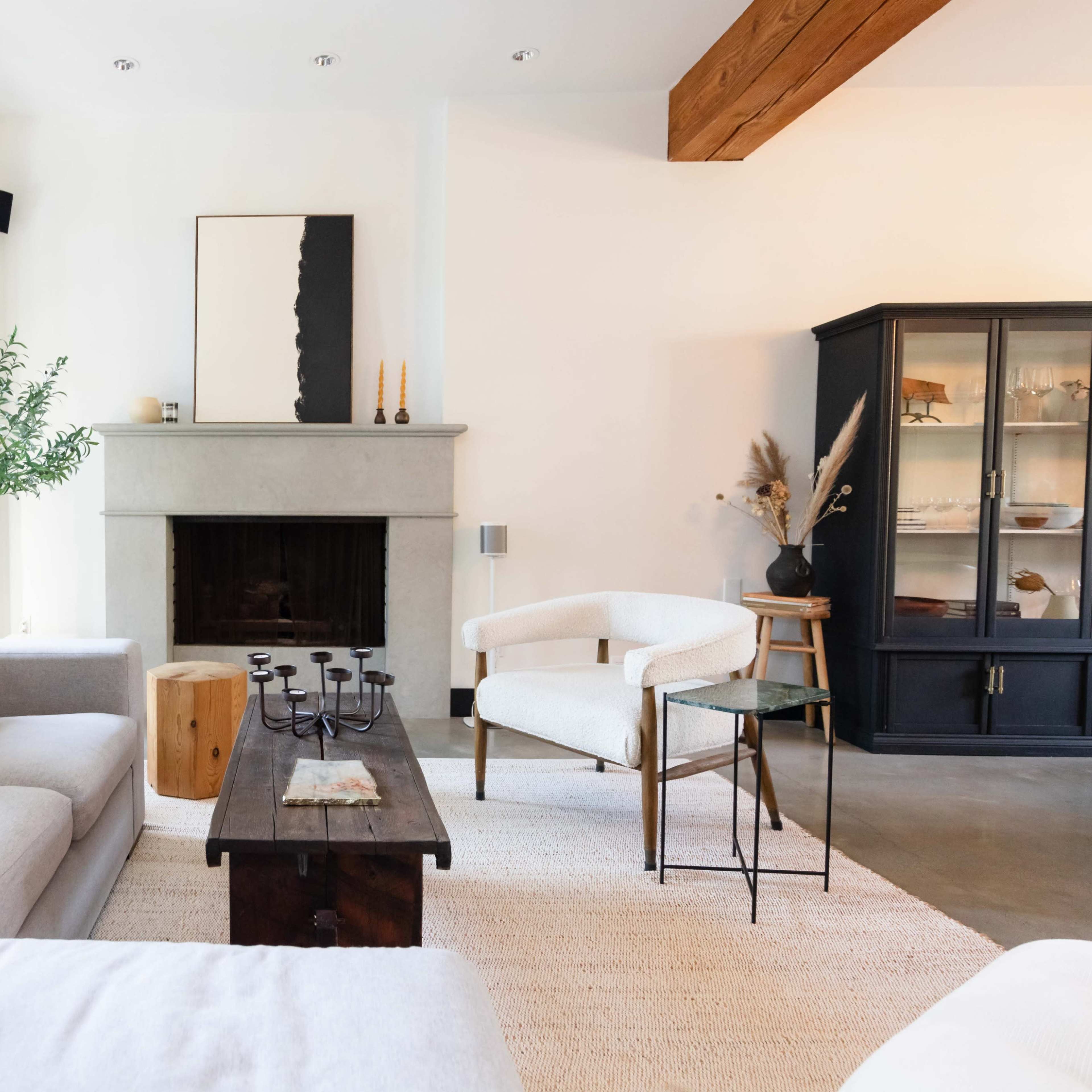 The living room features a gray sofa, a wooden coffee table, and a minimalist fireplace with a black framed cabinet against a white wall.