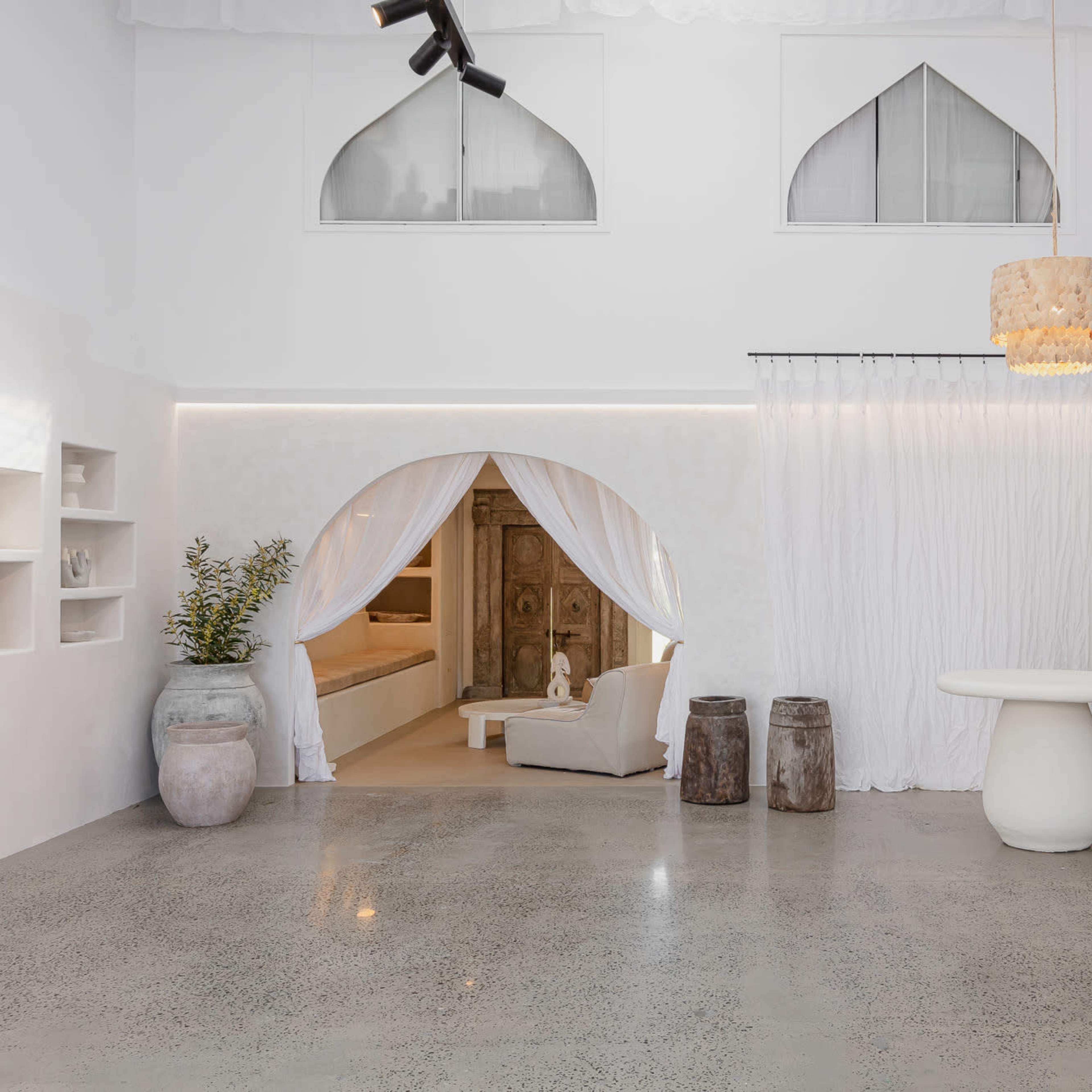 A spacious, modern interior with white walls, a minimalist decor, and a staircase leading to an upper level.