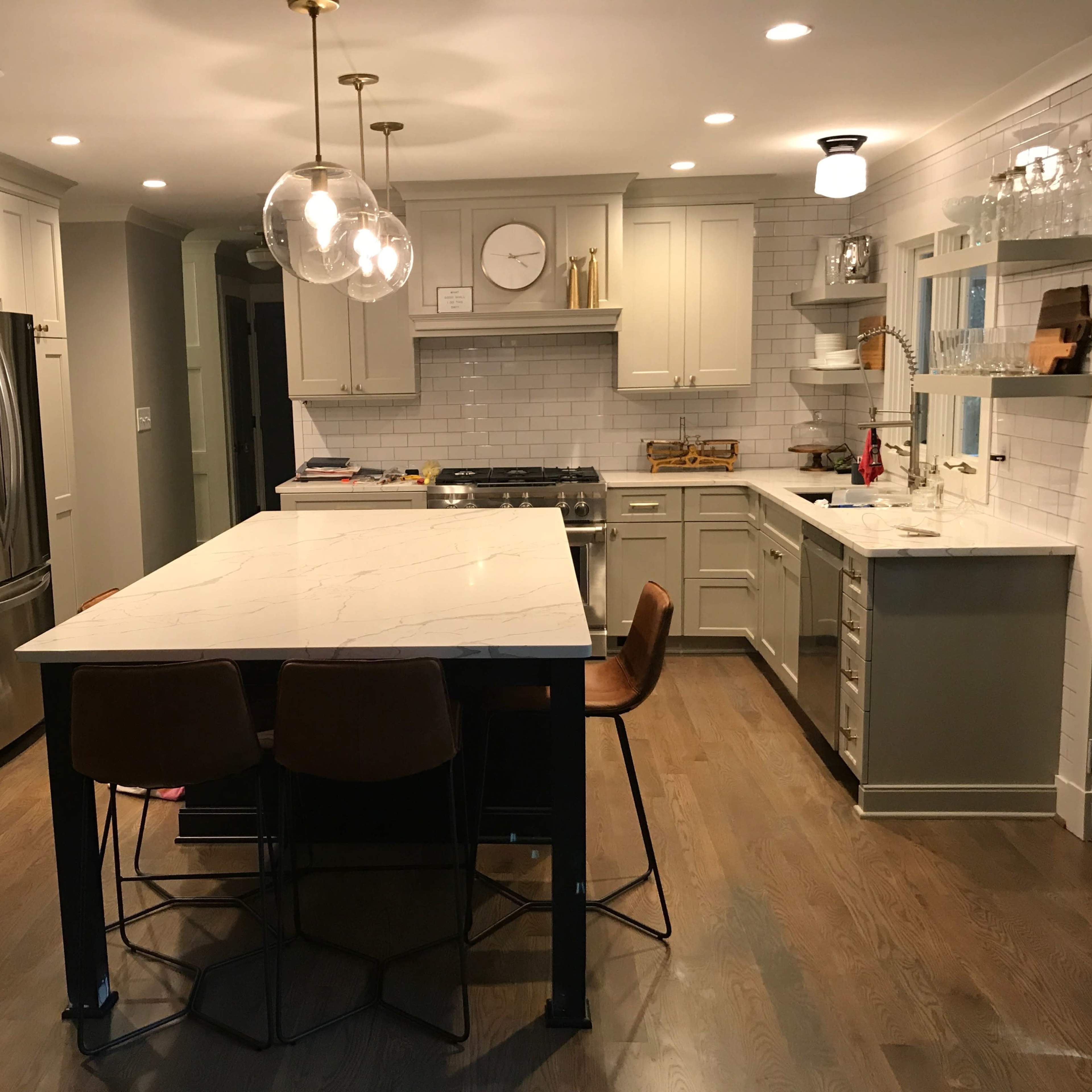 A modern kitchen with a large island, stainless steel appliances, and light-colored cabinetry.