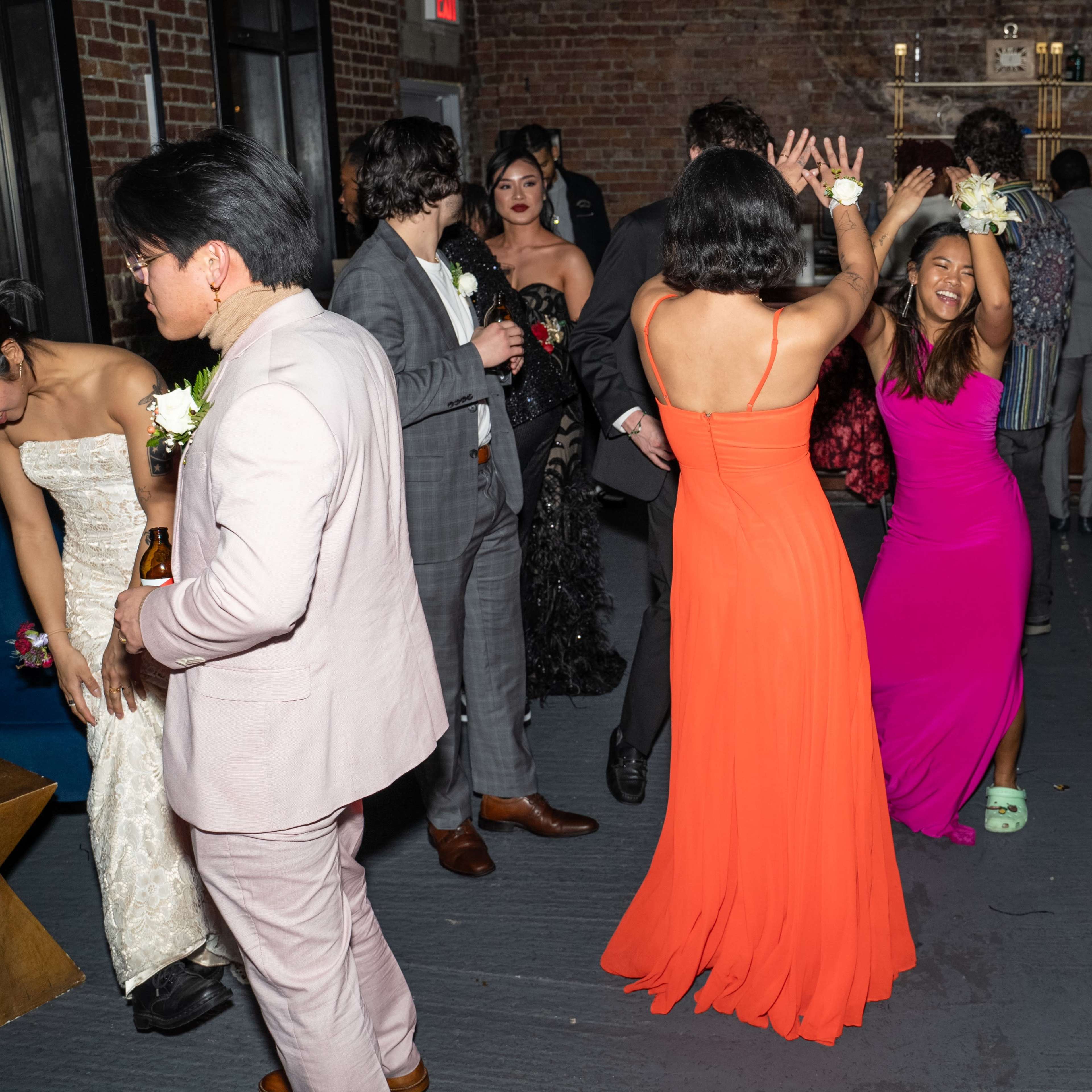 A group of people is dancing at a celebration in a venue with brick walls.