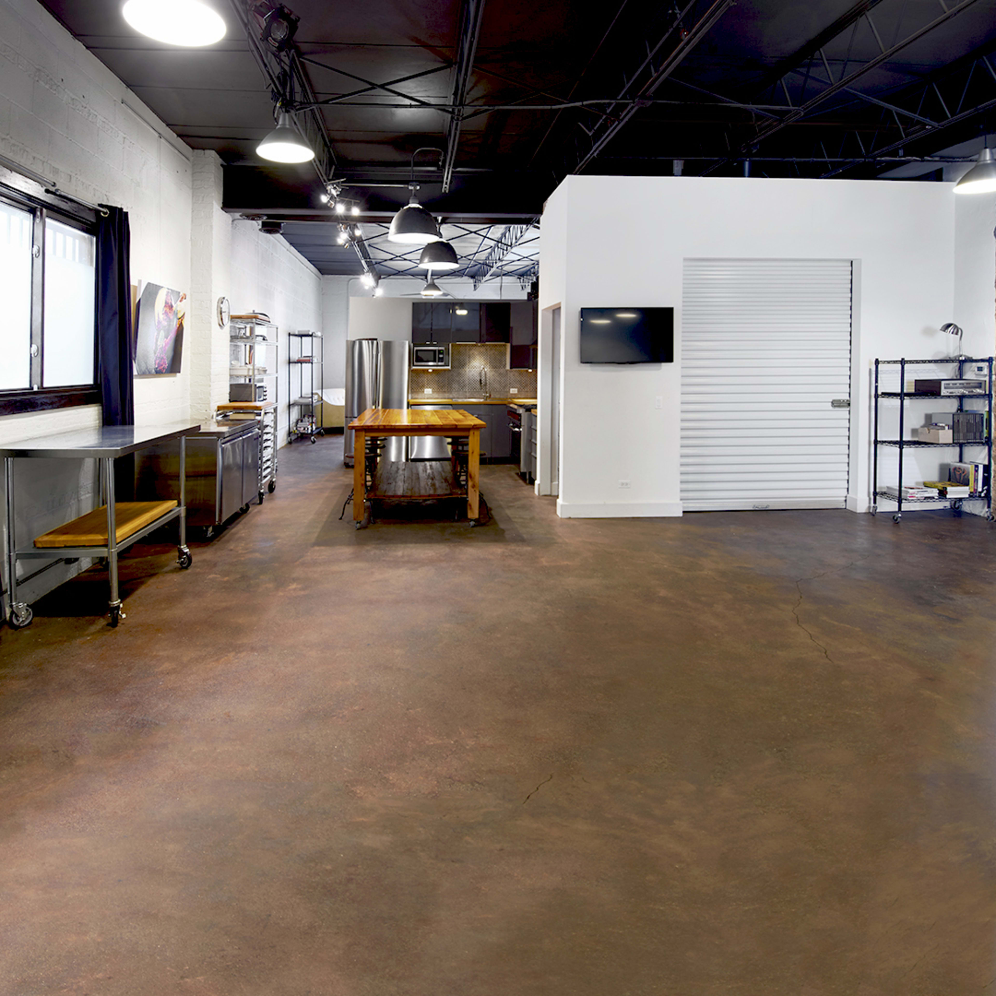 An industrial-style kitchen space with exposed brick walls, a large work table, and a sliding door.