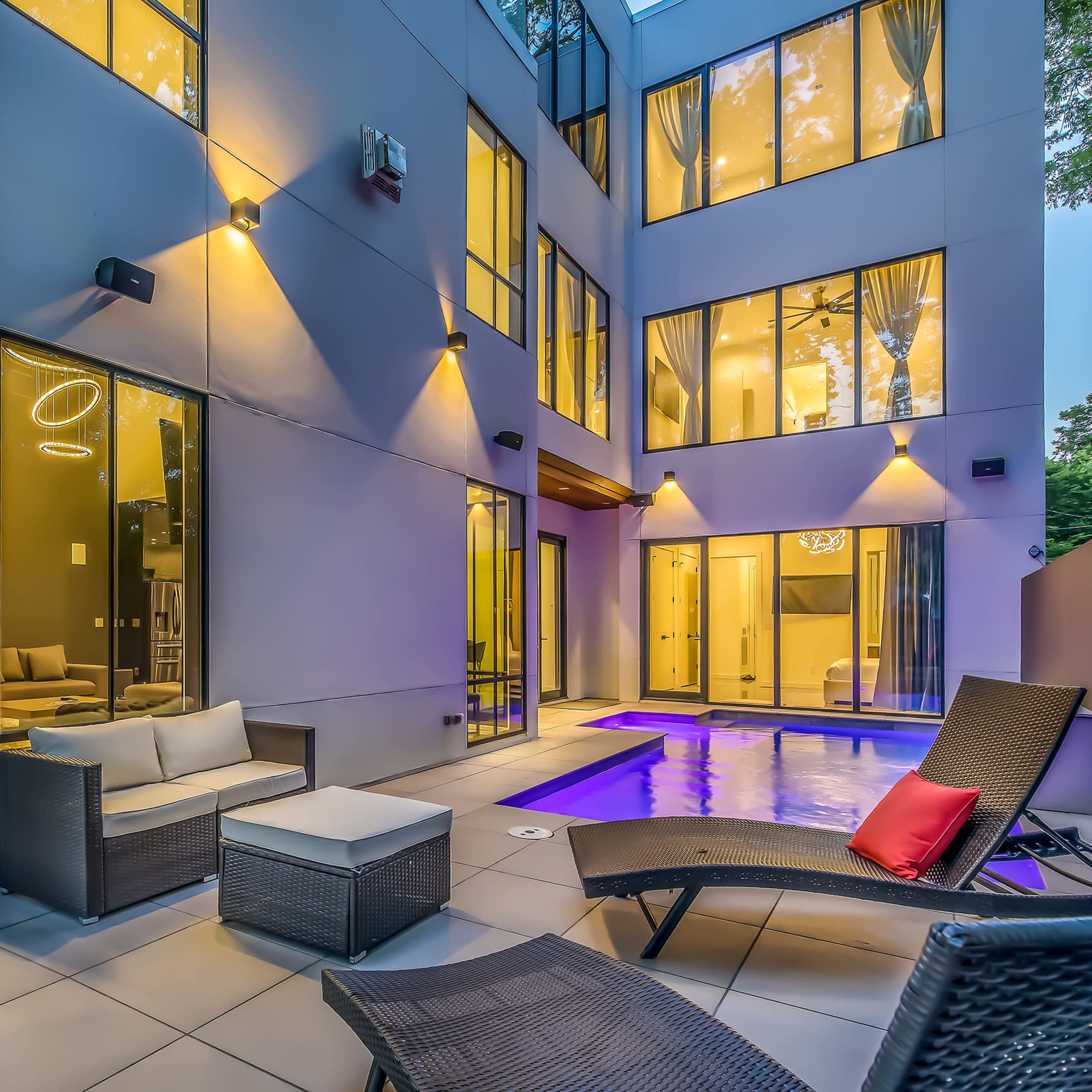 A modern patio with a swimming pool, surrounded by large windows and outdoor seating arrangements in a contemporary architectural setting.