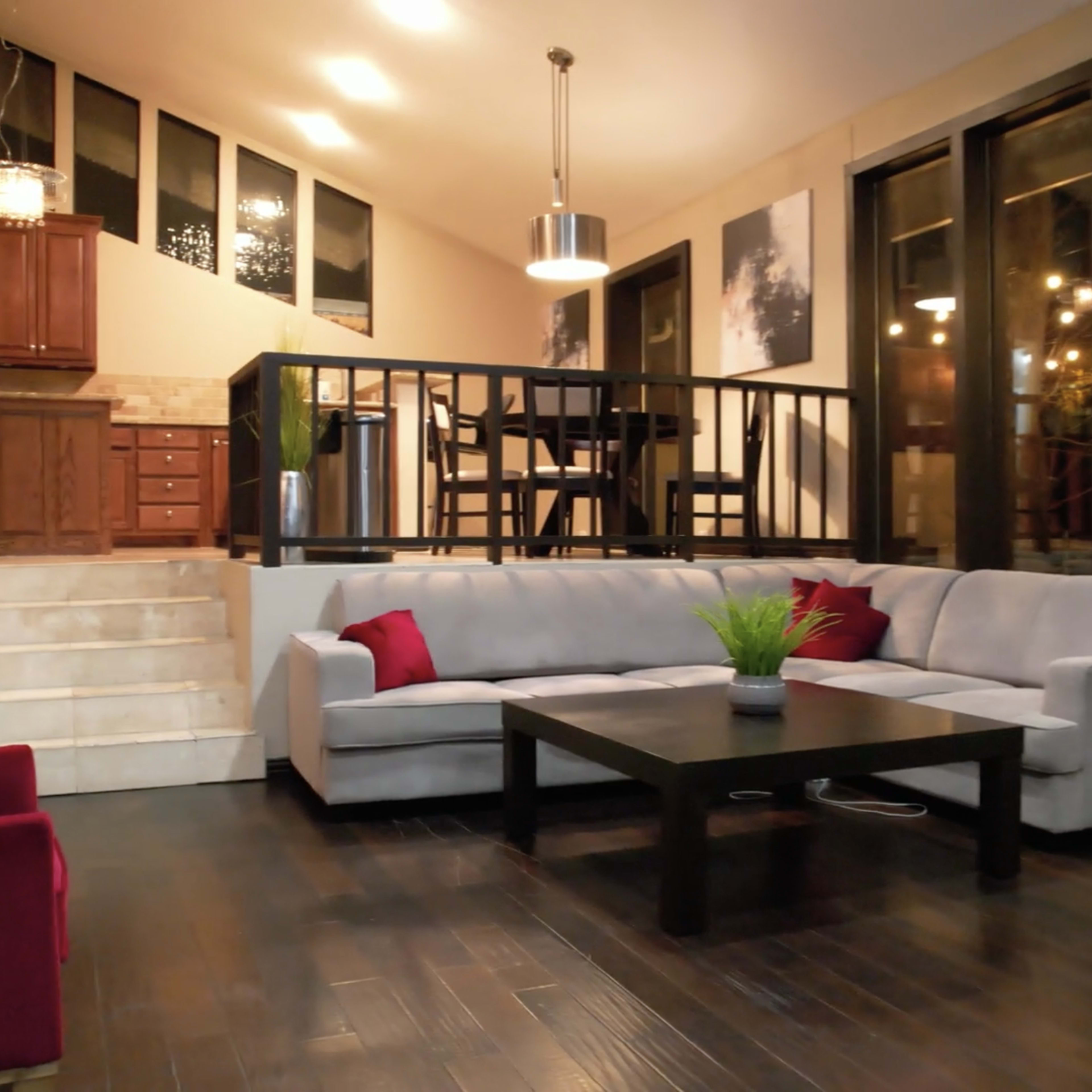 A modern living room with a gray sectional sofa, a black coffee table, and large windows allowing natural light to enter the space.