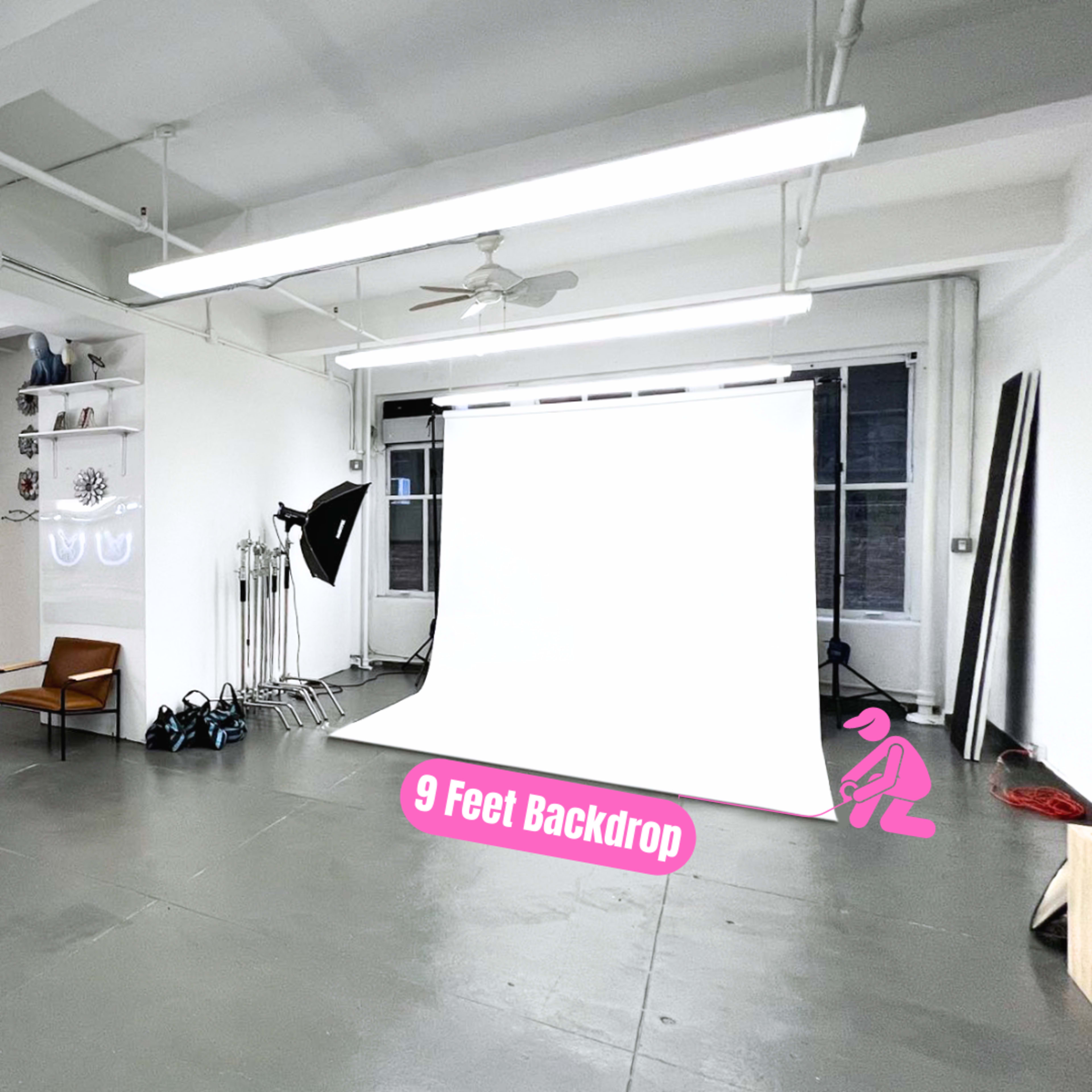 A professional photography studio with a makeup station, a 9-foot backdrop, and various lighting equipment.